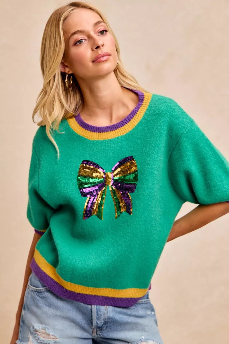 BiBi Mardi Gras Sequin Ribbon Patched Sweater with vibrant sequin bow detail in festive colors.