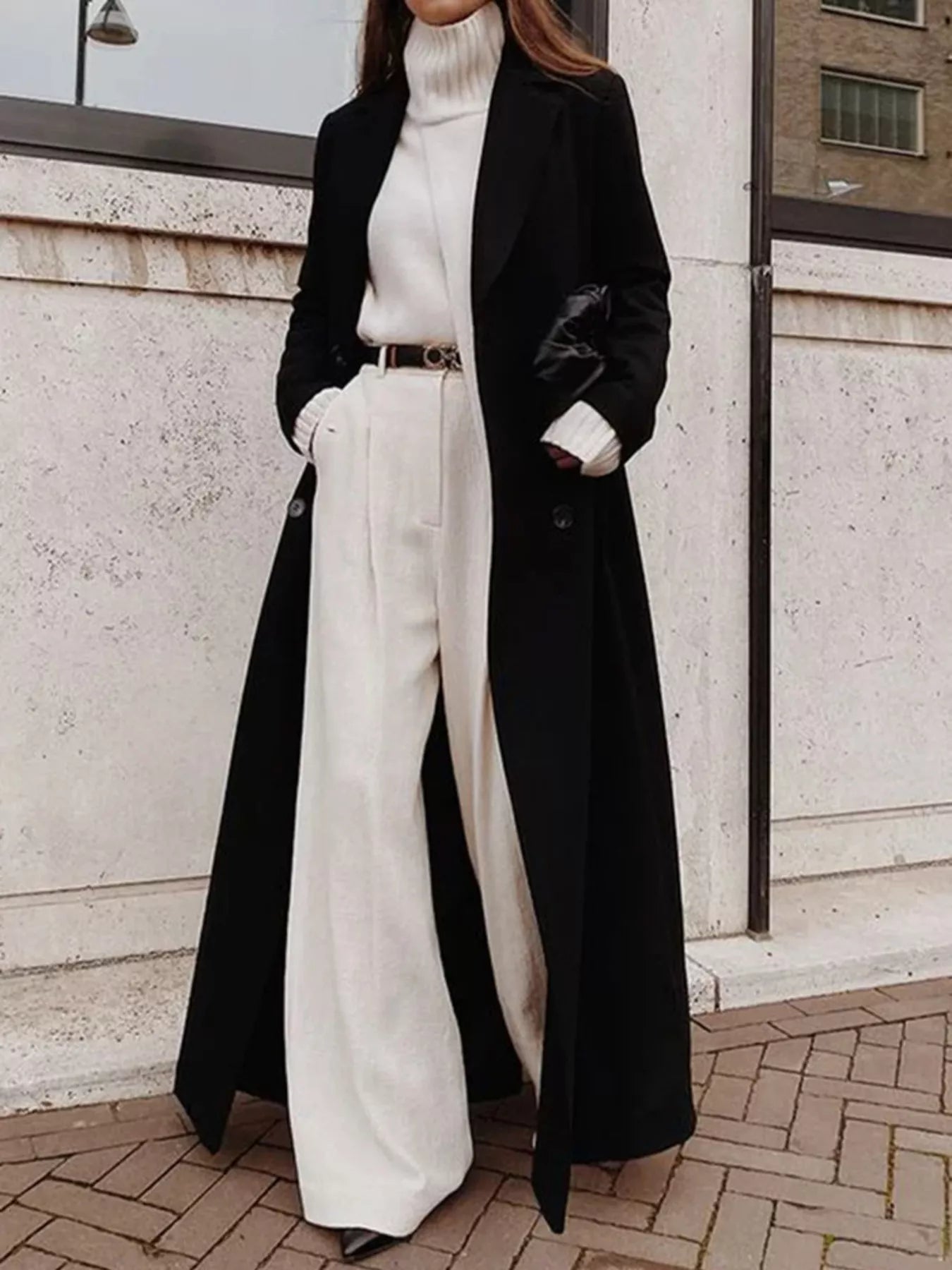 Model wearing a Double Breasted Longline Overcoat over a white turtleneck and wide-leg pants, showcasing an elegant classic style.