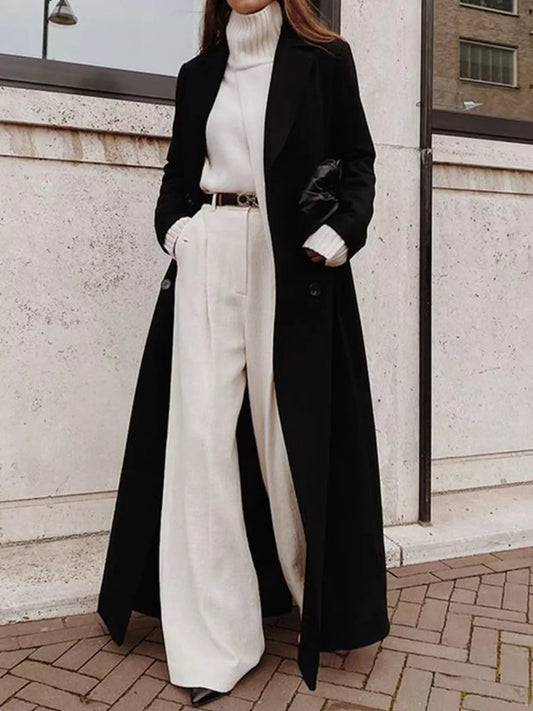 Model wearing a Double Breasted Longline Overcoat over a white turtleneck and wide-leg pants, showcasing an elegant classic style.