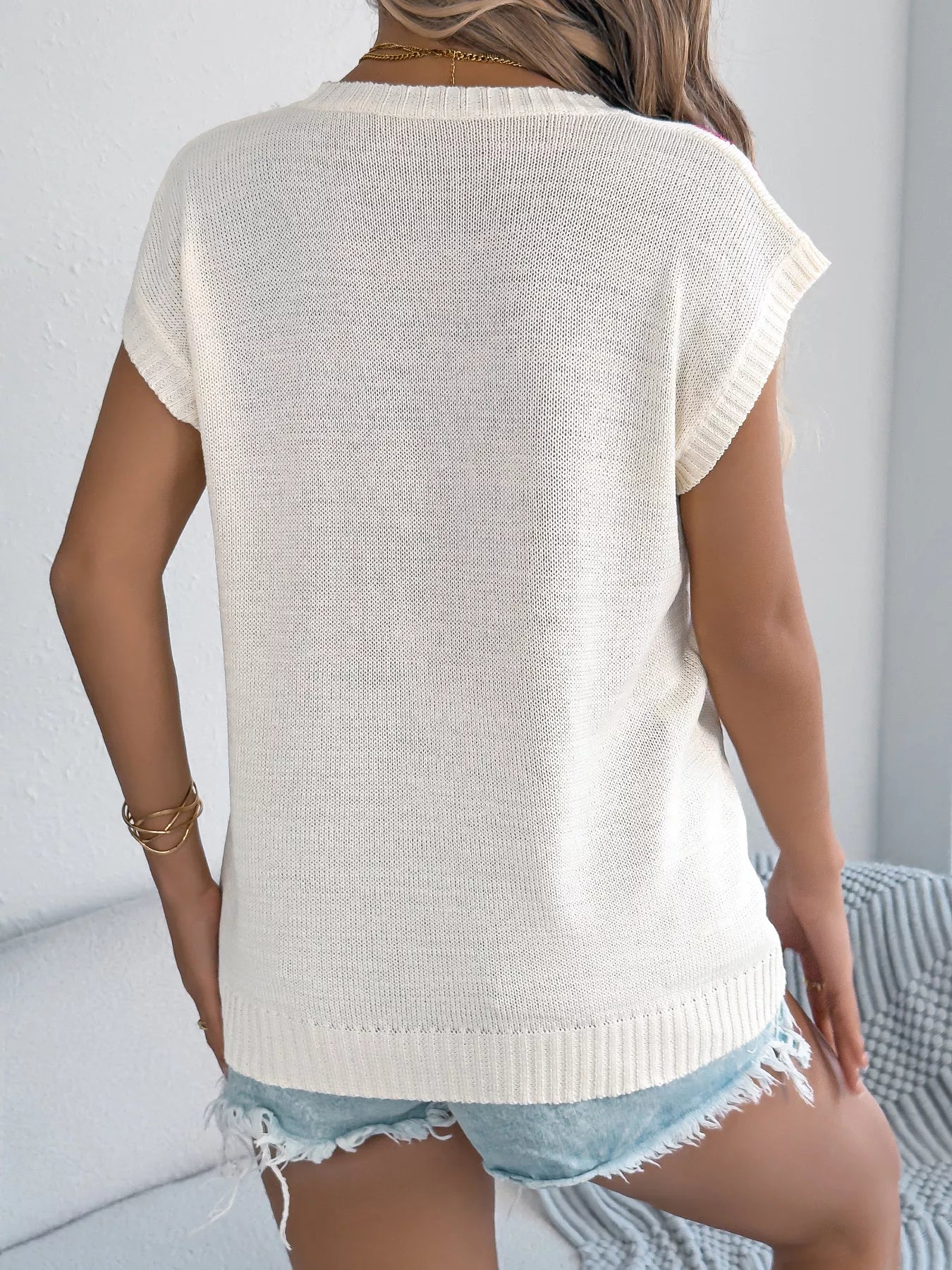 Back view of a woman wearing a Flower Round Neck Sweater with a casual style, paired with denim shorts.