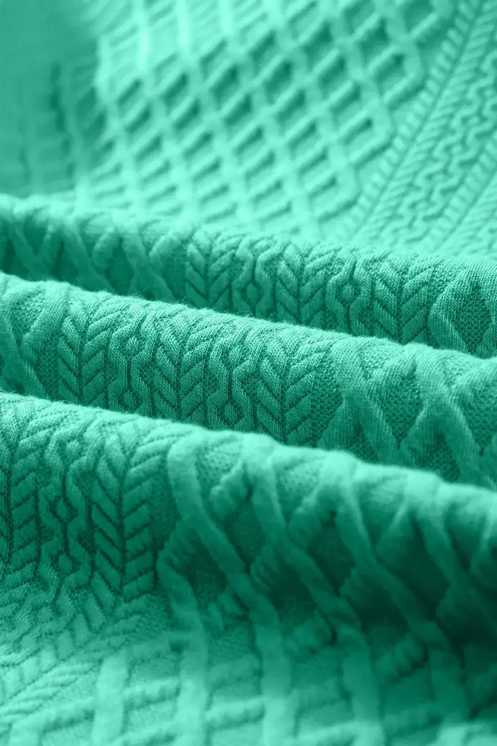 Close-up of textured turquoise fabric showcasing intricate patterns and soft folds.
