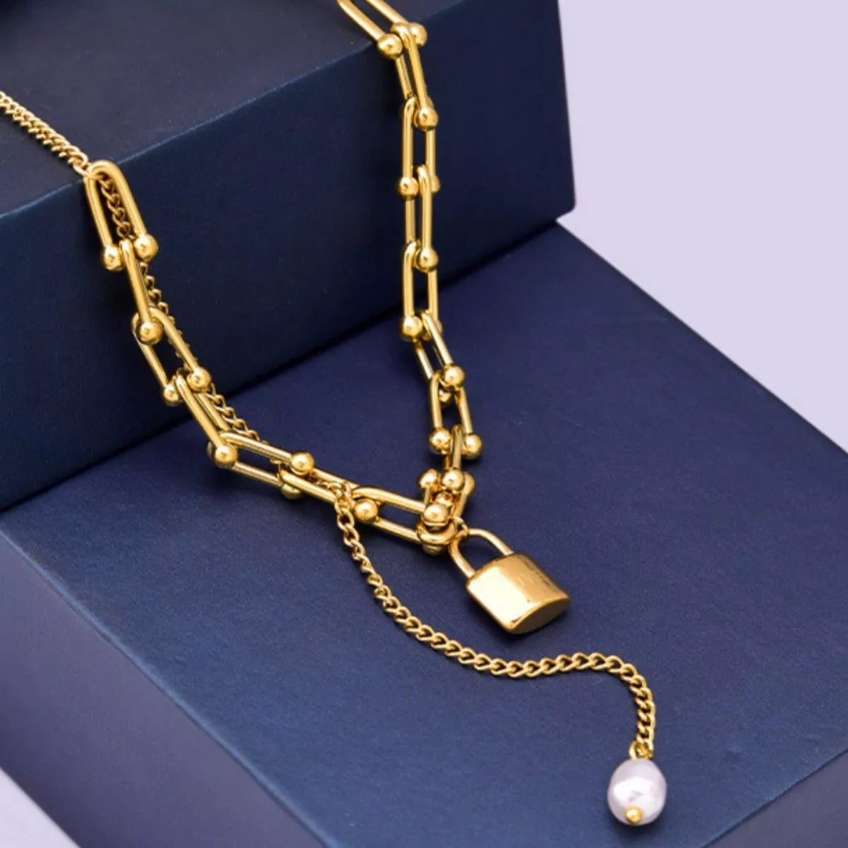 18K Gold-Plated Lock Pendant Necklace featuring a synthetic pearl and unique chain design on a navy box.