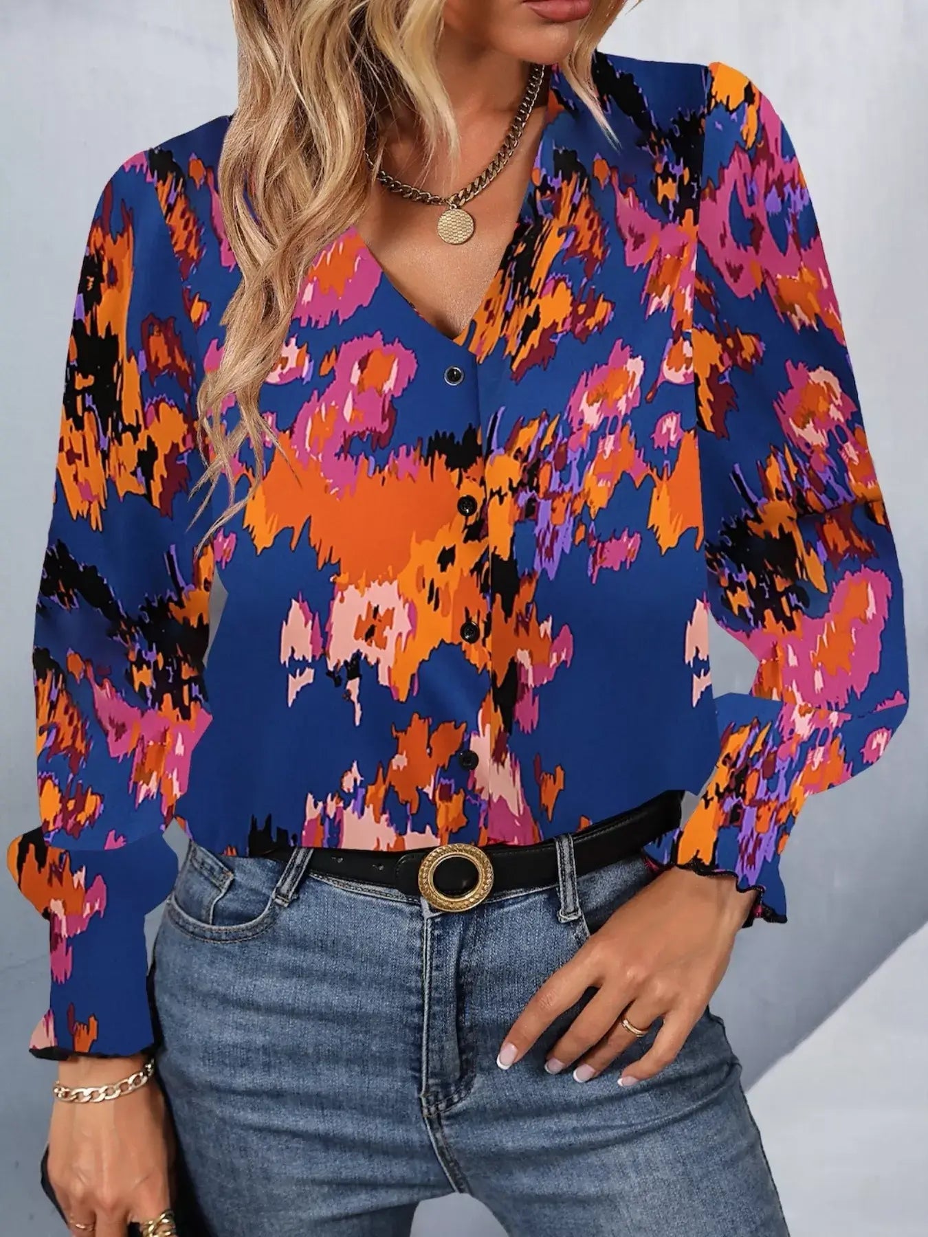 Printed button up long sleeve shirt featuring vibrant abstract patterns in blue, orange, and purple, paired with jeans.