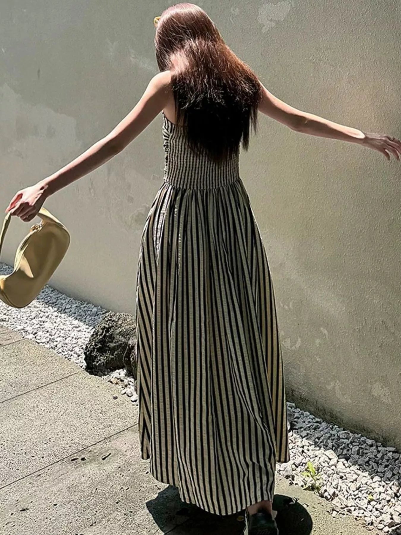 Striped Spaghetti Strap Casual Maxi Dress for summer wear, showcasing the back view and standing in a sunny outdoor setting.