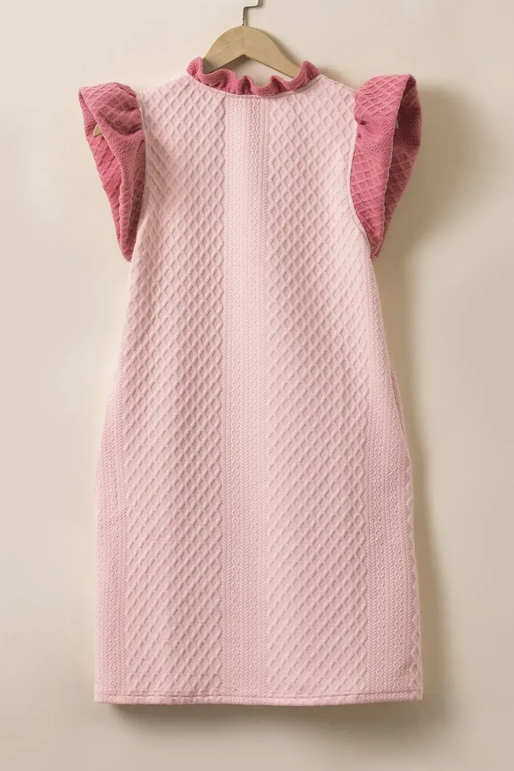 Back view of a ruffled V-neck cap sleeve mini dress in soft pink, featuring textured fabric and cap sleeves.