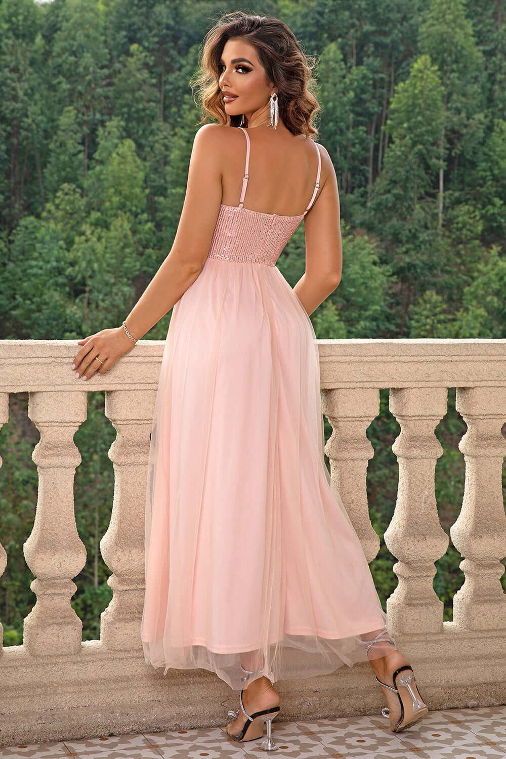 Elegant woman in Spaghetti Strap Slit Mesh Dress, showcasing back view with flowing skirt against a lush background.