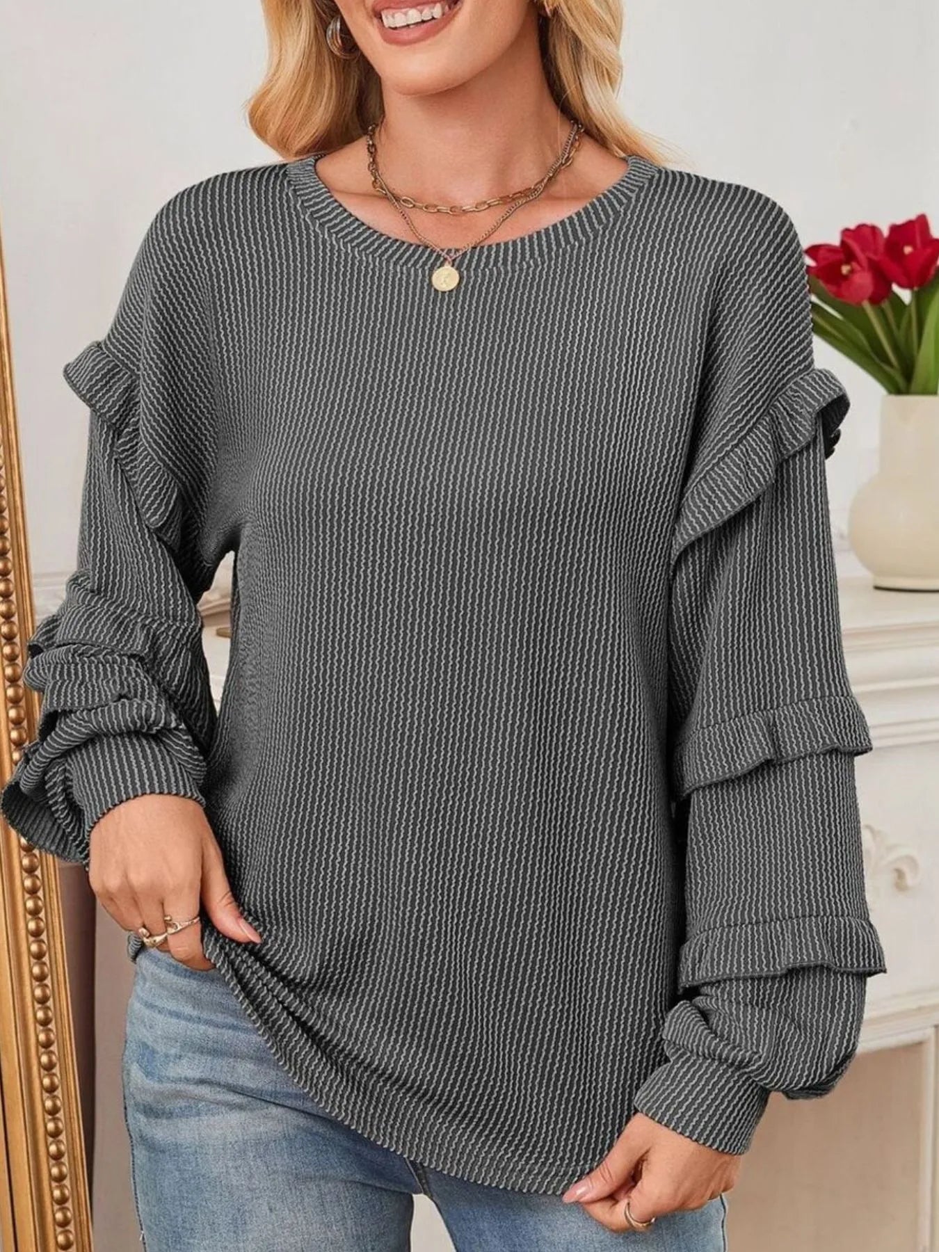 Woman wearing a Ruffled Round Neck Long Sleeve Sweatshirt in gray with ribbed texture and ruffled sleeves.