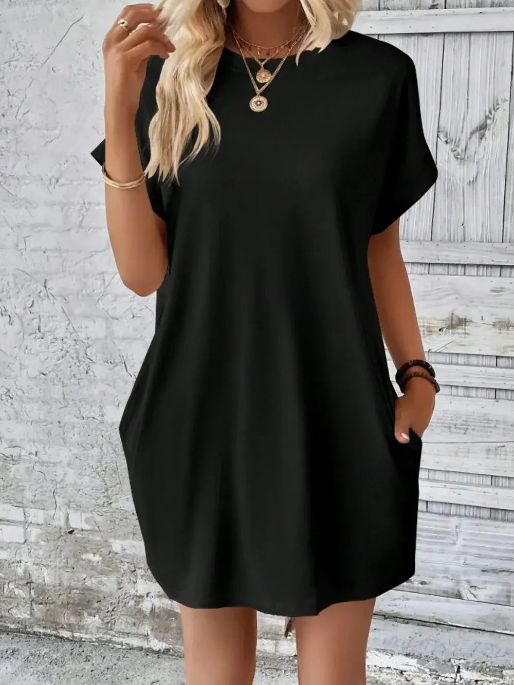 Model wearing a black pocketed round neck short sleeve dress, showcasing casual style and comfort.