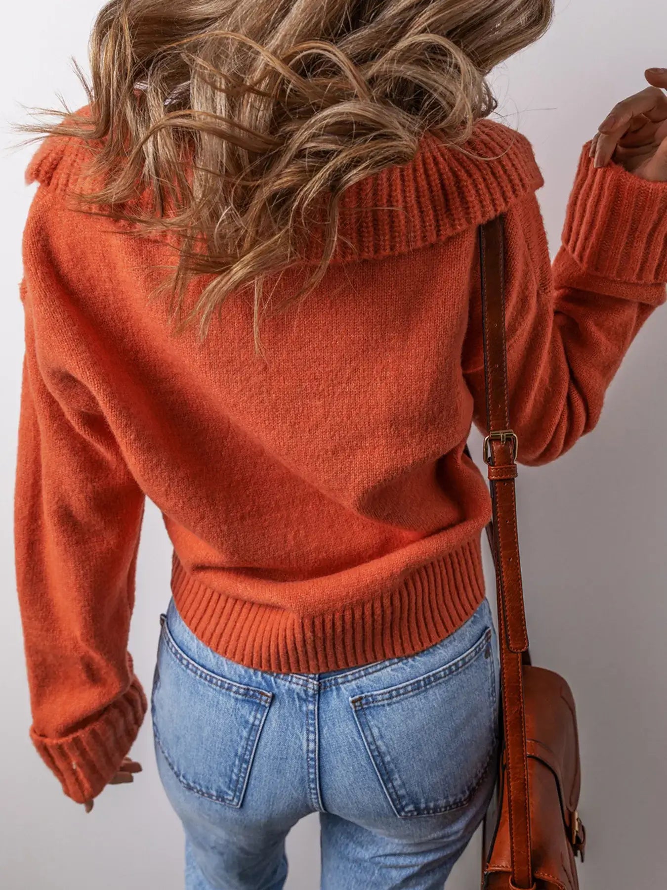 Woman wearing a collared v neck ribbed edge sweater in orange with a stylish back view, showcasing ribbed details.