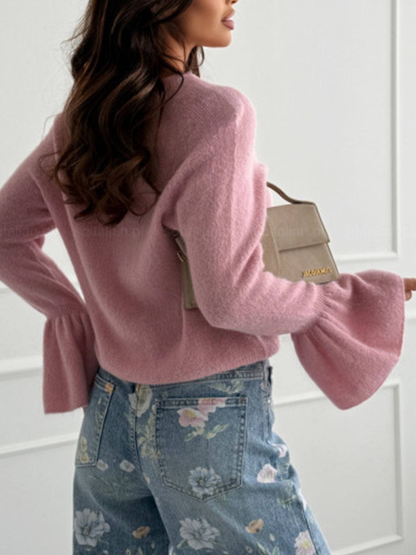 Round Neck Flounce Sleeve Sweater in pink, featuring bell sleeves, paired with floral jeans and a stylish handbag.
