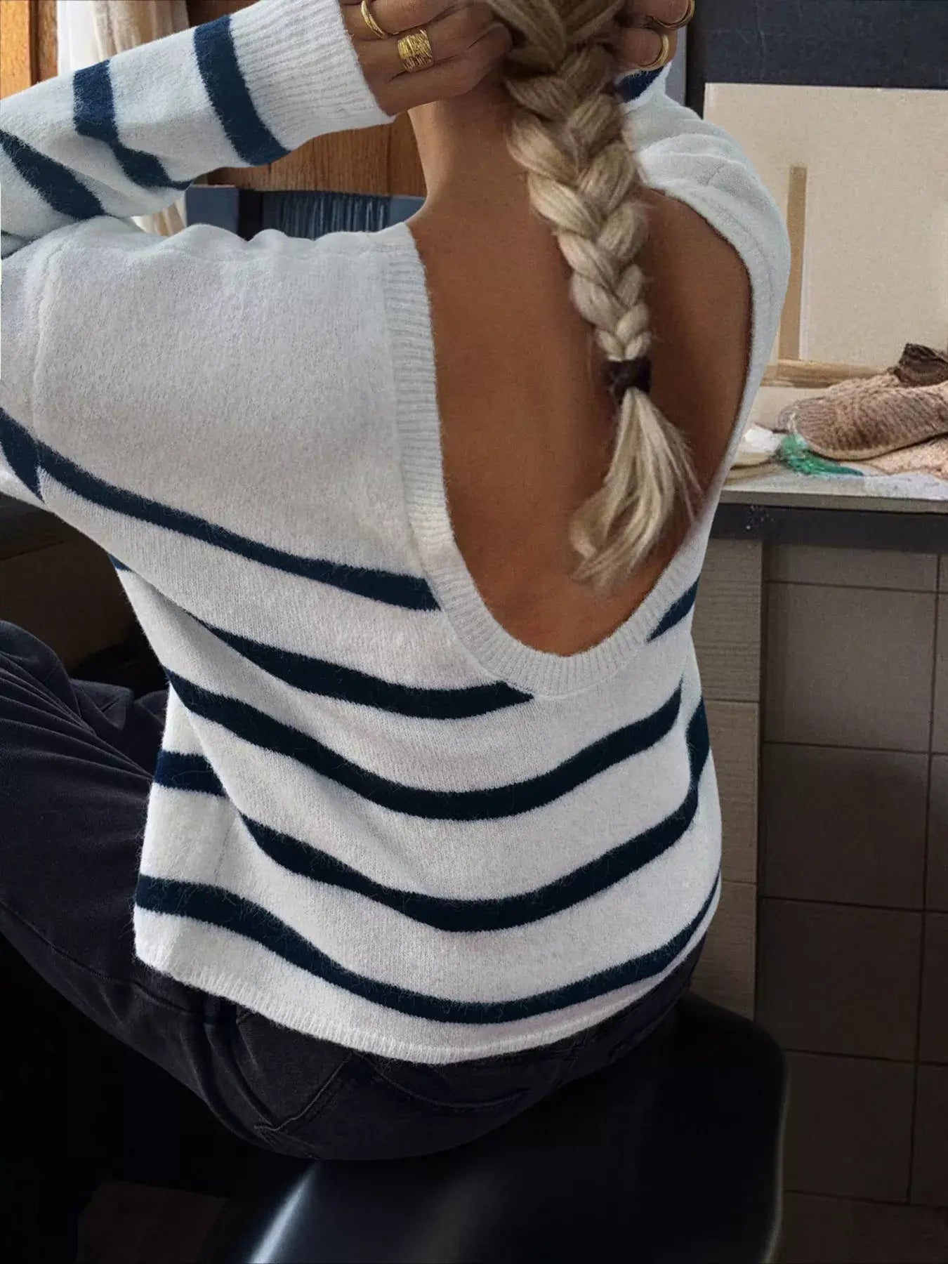 Striped round neck long sleeve knit top showcasing a modern design with an open back and playful striped pattern.