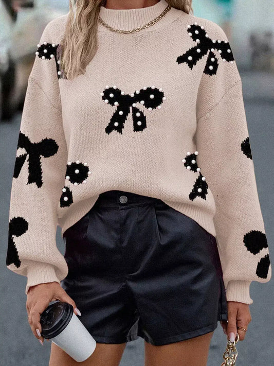 Woman wearing a pearl embellished bow pattern loose sweater with black shorts, exuding elegance and style.