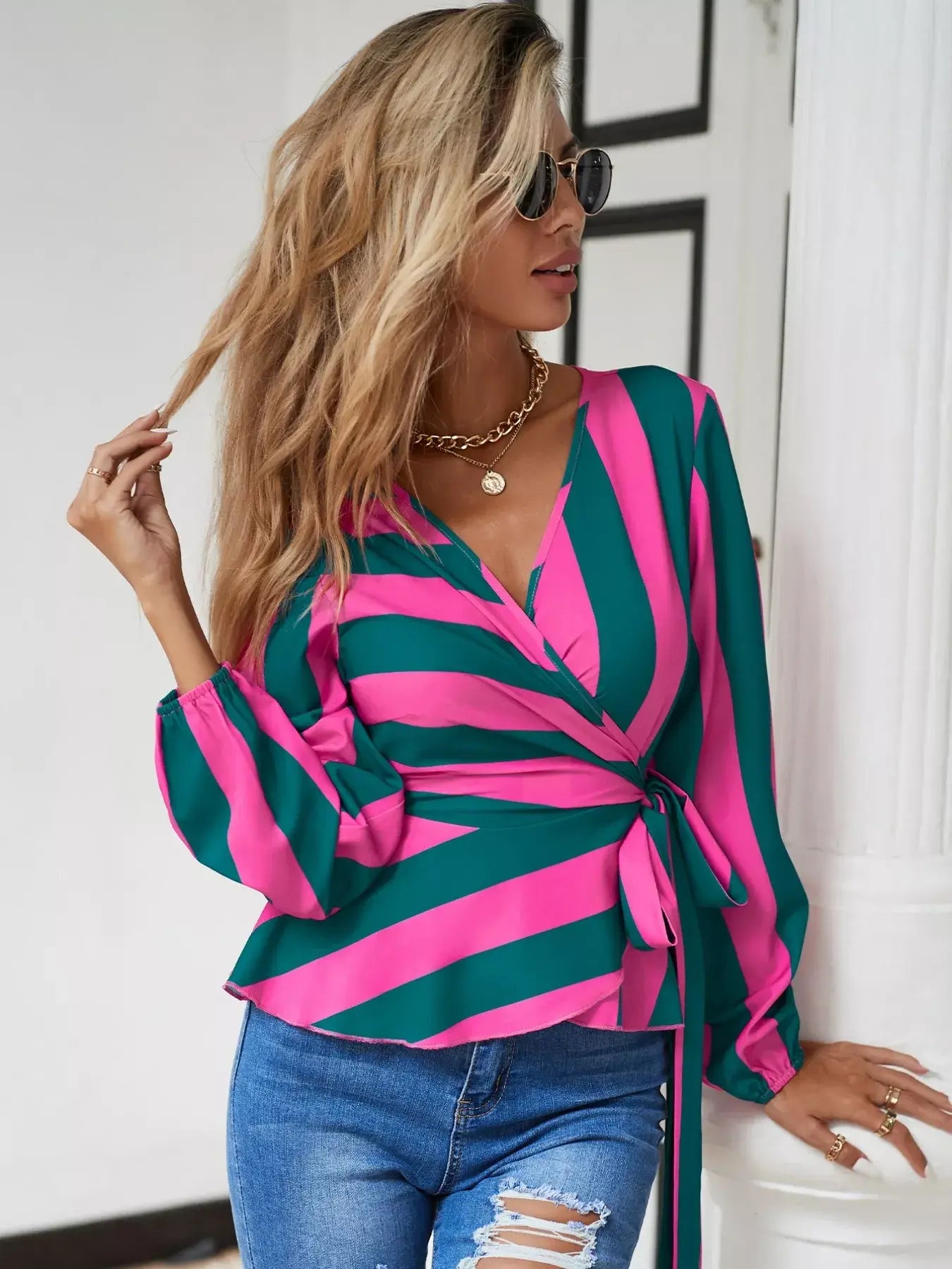 Striped wrap blouse with tie detail in pink and green, styled with distressed jeans for a chic everyday look.