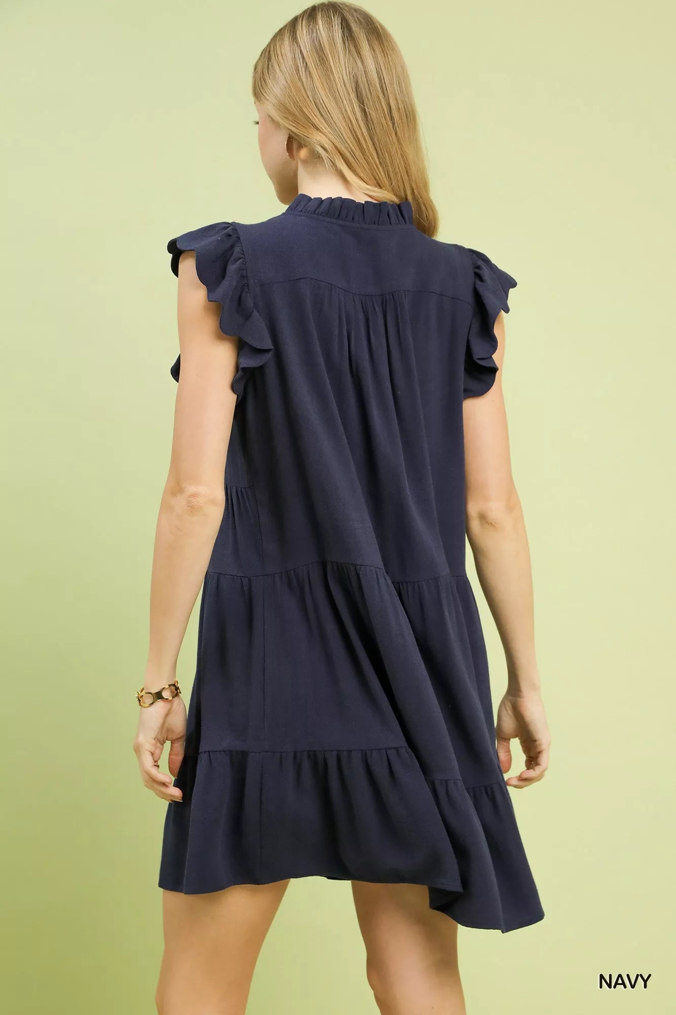 Model wearing the Umgee Linen Tiered Baby Doll Dress in navy showcasing its tiered design and flutter sleeves.