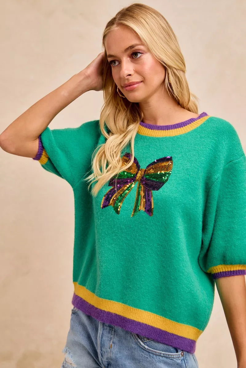 BiBi Mardi Gras Sequin Ribbon Patched Sweater featuring vibrant sequin bow design in festive colors.