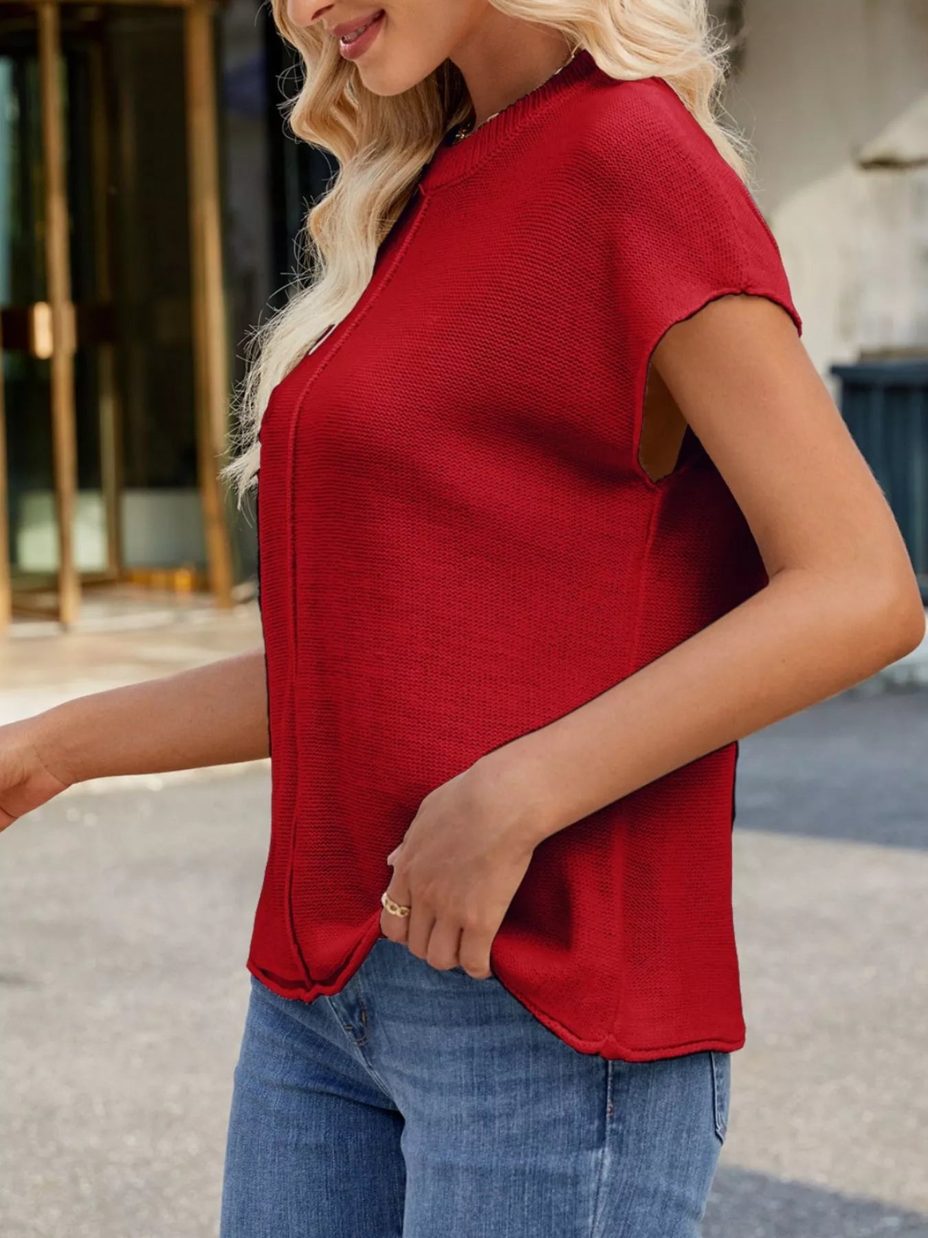 Model wearing a Round Neck Short Sleeve Knit Top with Center Seam Detail in red, paired with jeans.