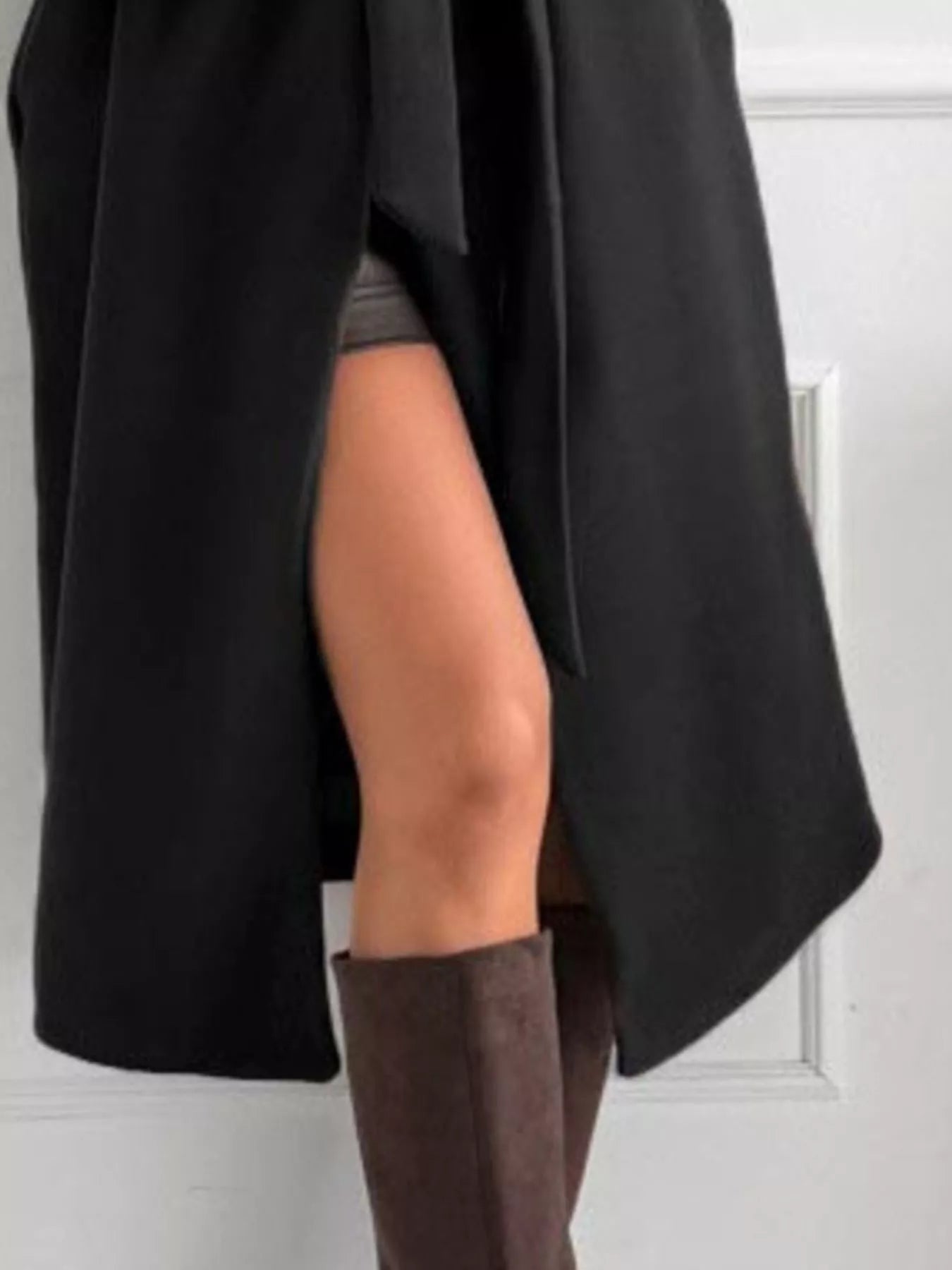 Tie Waist Longline Coat showcasing a belted design, featuring a side slit and stylish knee-high boots for an elegant look.