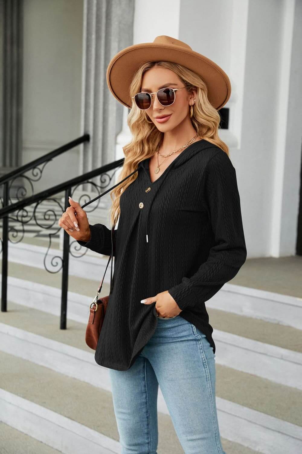 Long Sleeve Hooded Blouse in black worn with jeans, featuring a tie-neck design and stylish accessories.