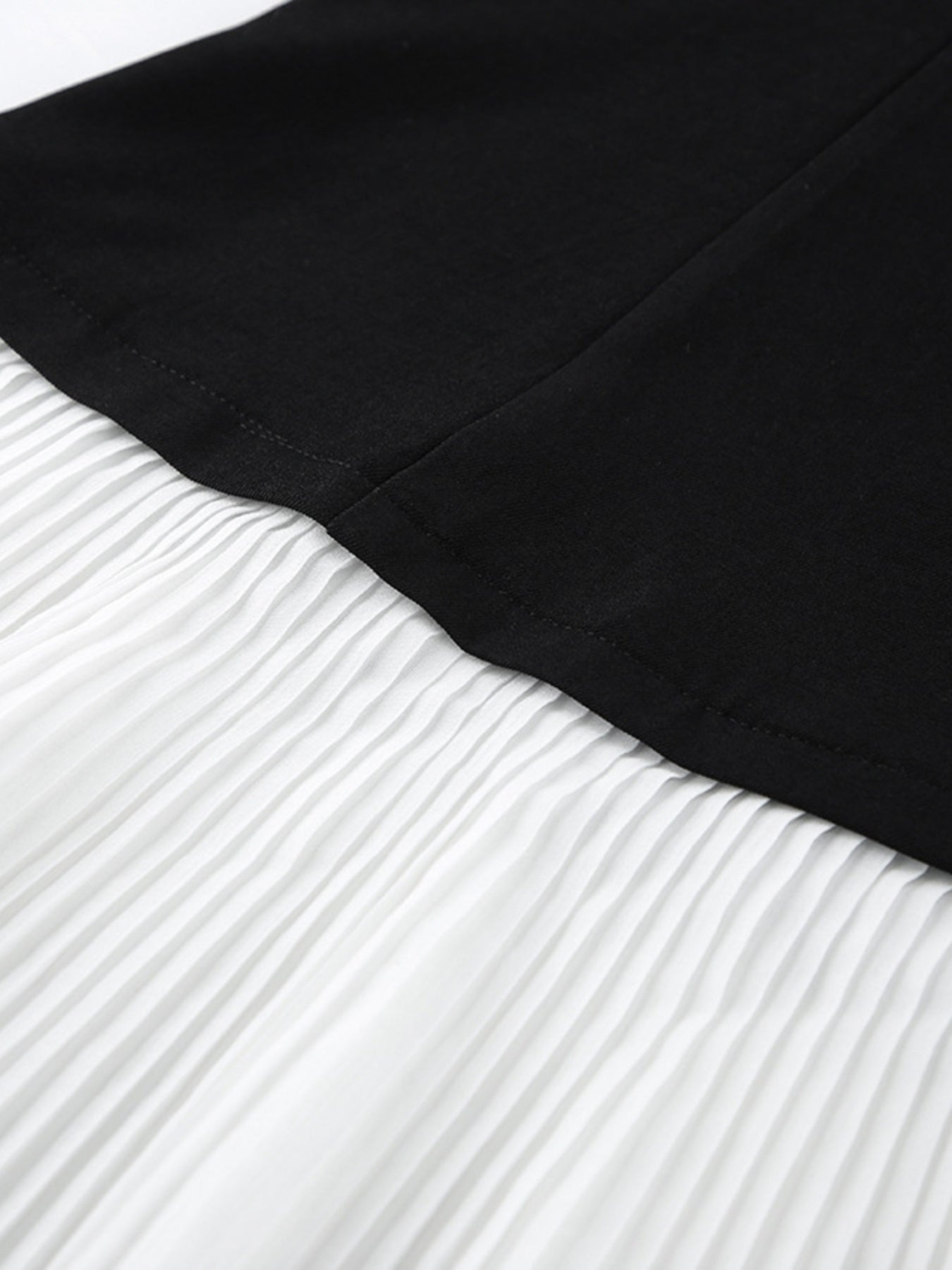 Pleated One Button Blazer Dress showing details of fabric texture and color contrast between black and white.