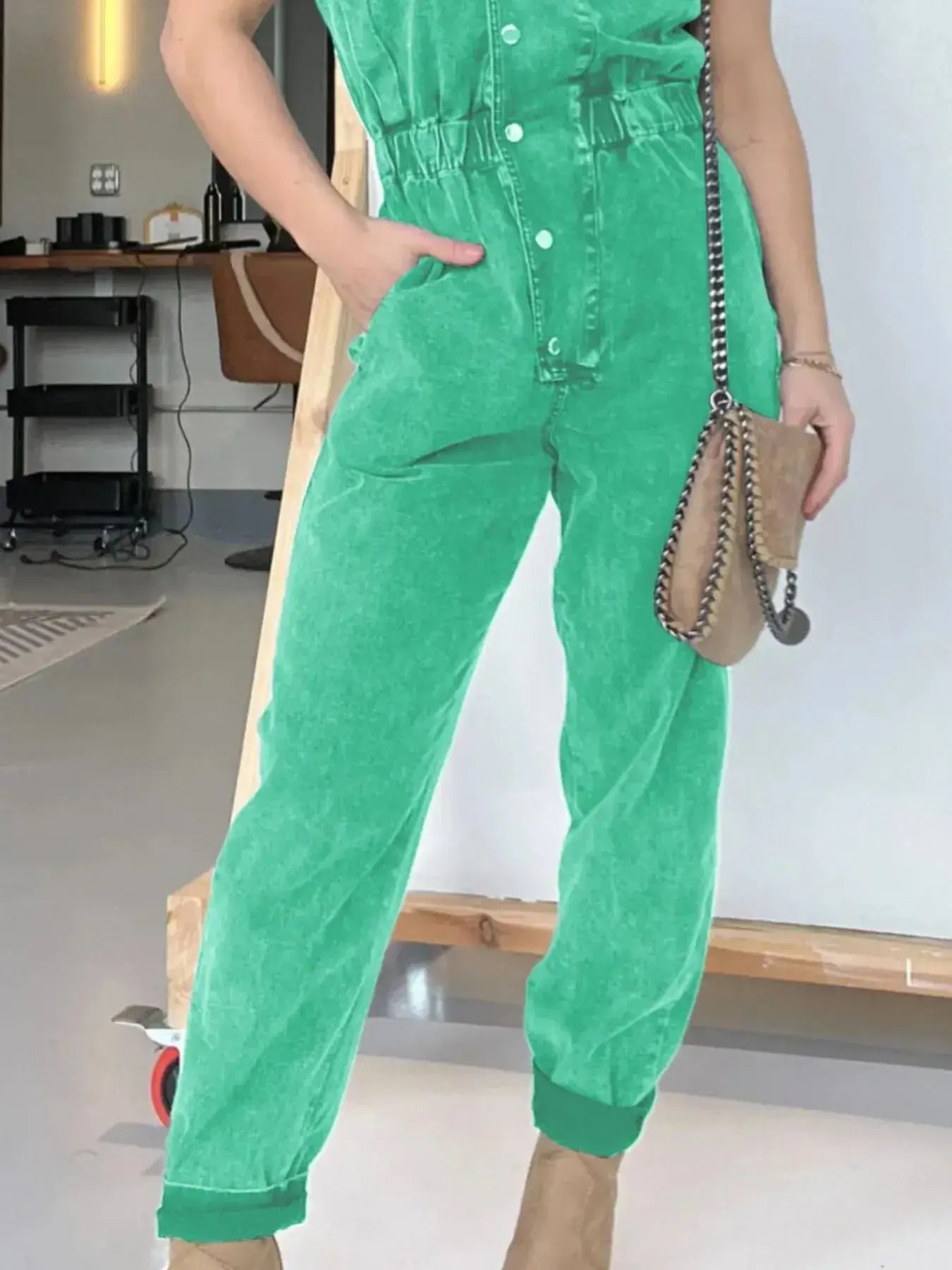 Bright green cap sleeve denim jumpsuit with button front and pockets, styled for a casual look.