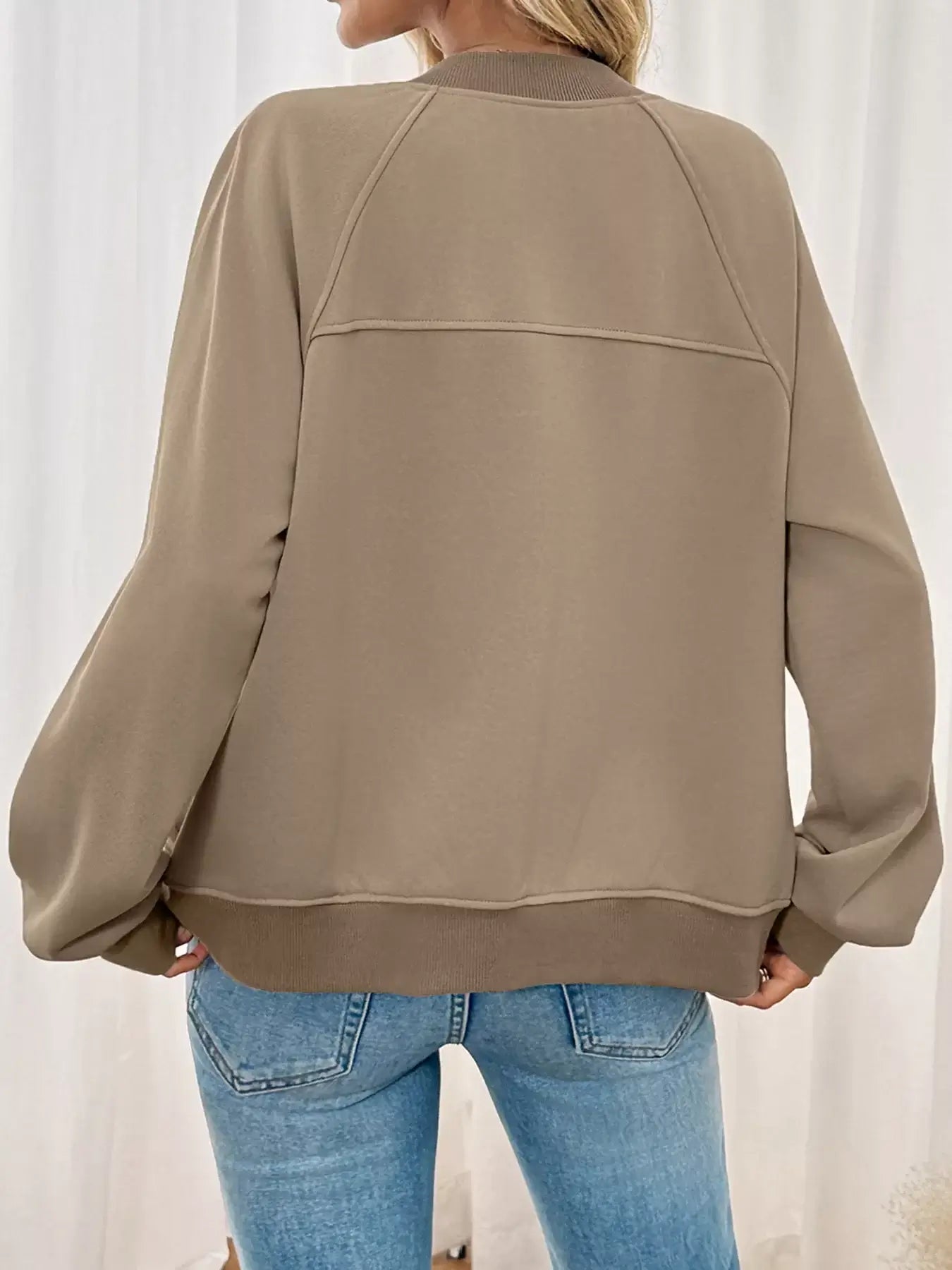 Back view of a woman wearing a Zip Up Raglan Sleeve Jacket in beige, showcasing the comfortable fit and raglan sleeves.