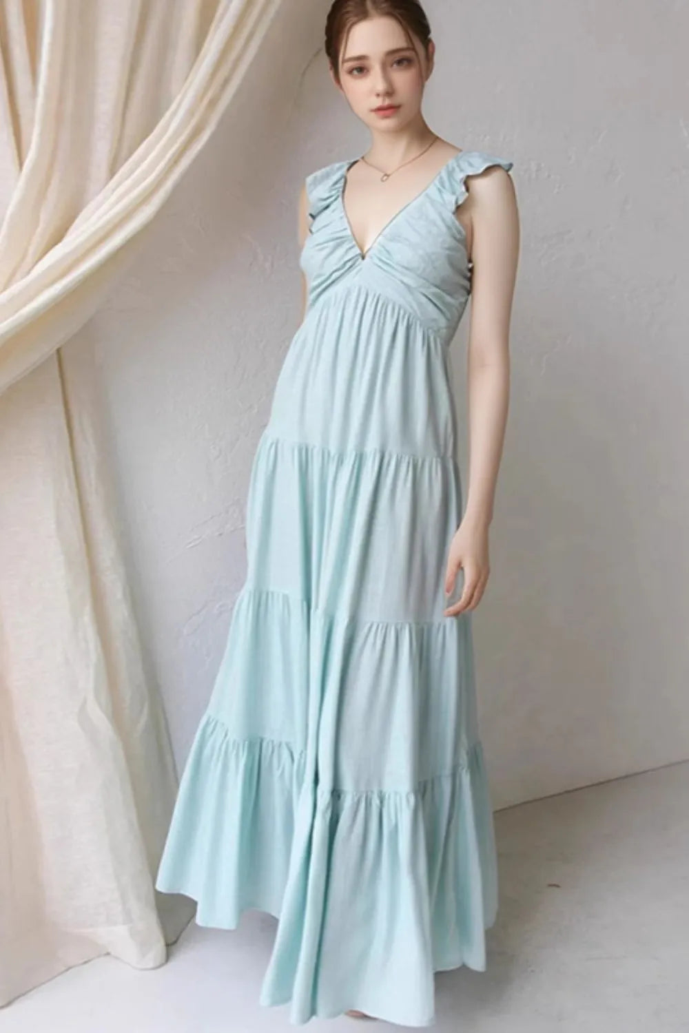 Ruffled V-Neck Tiered Dress in light blue color, featuring ruffles and tiered design, shown in a stylish setting.