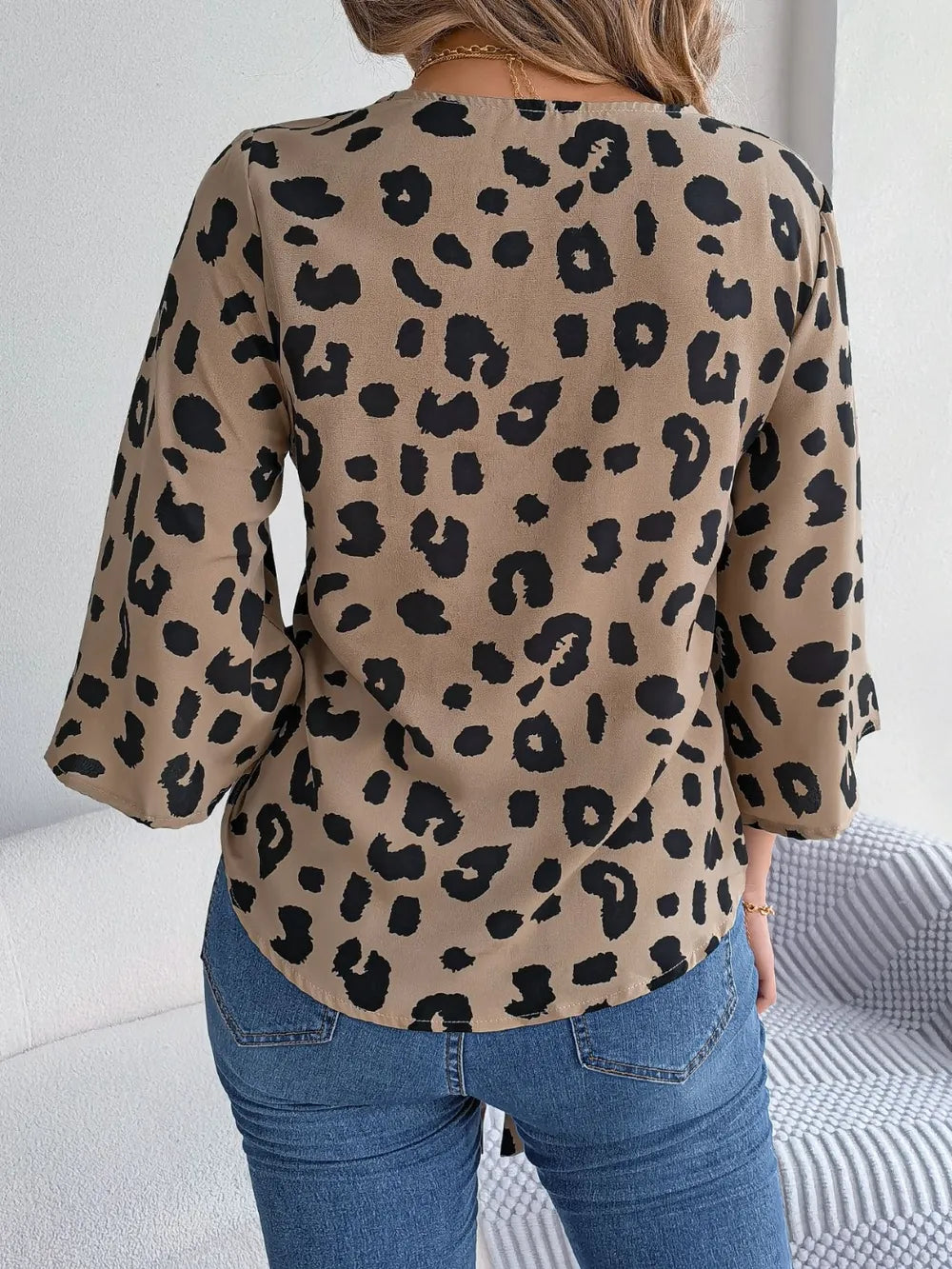 Back view of Tied Button Up Leopard V-Neck Blouse showcasing black leopard spots on a tan background.