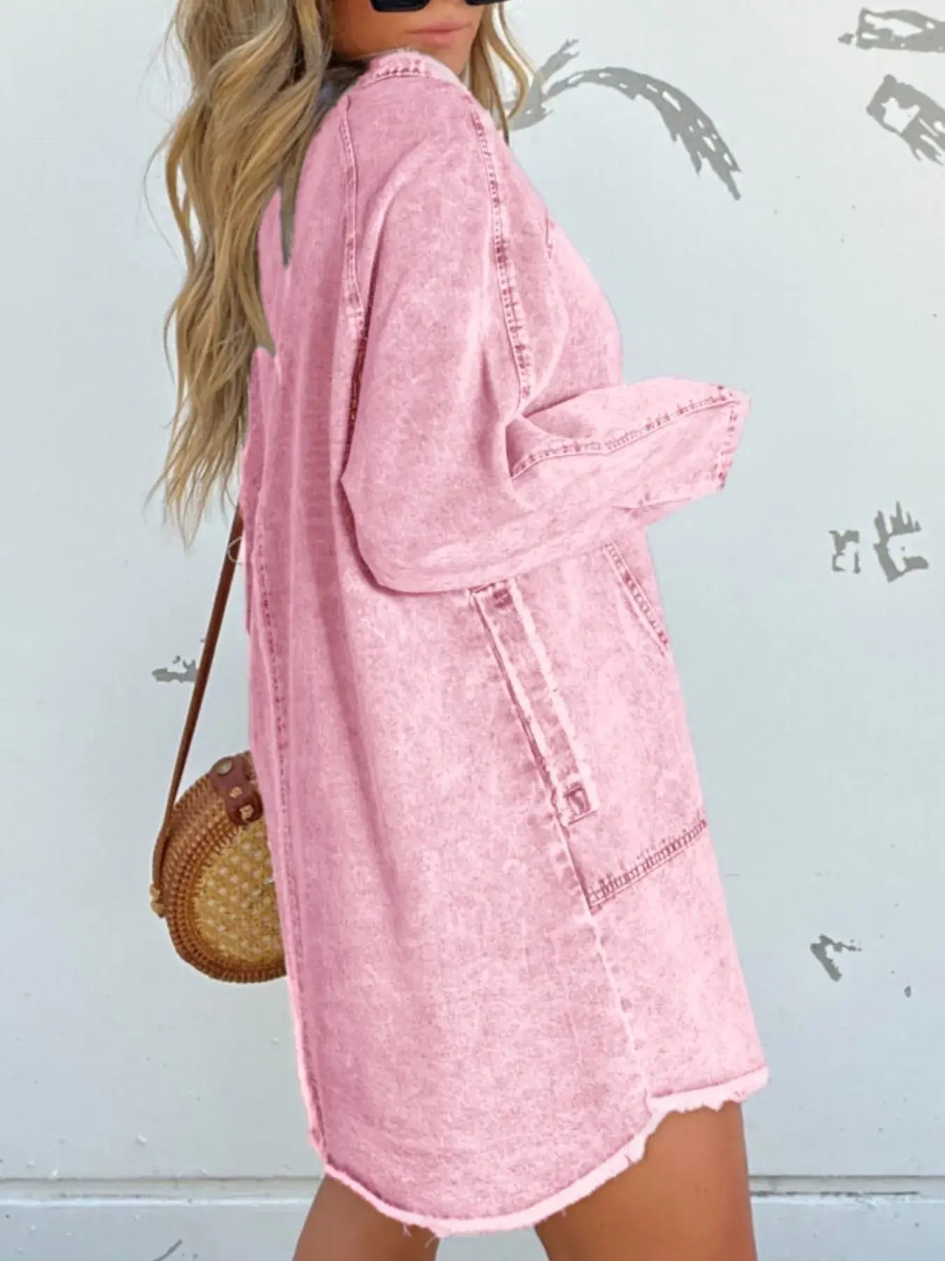 Woman wearing a pink denim shirt dress with long sleeves and functional pockets, styled casually.