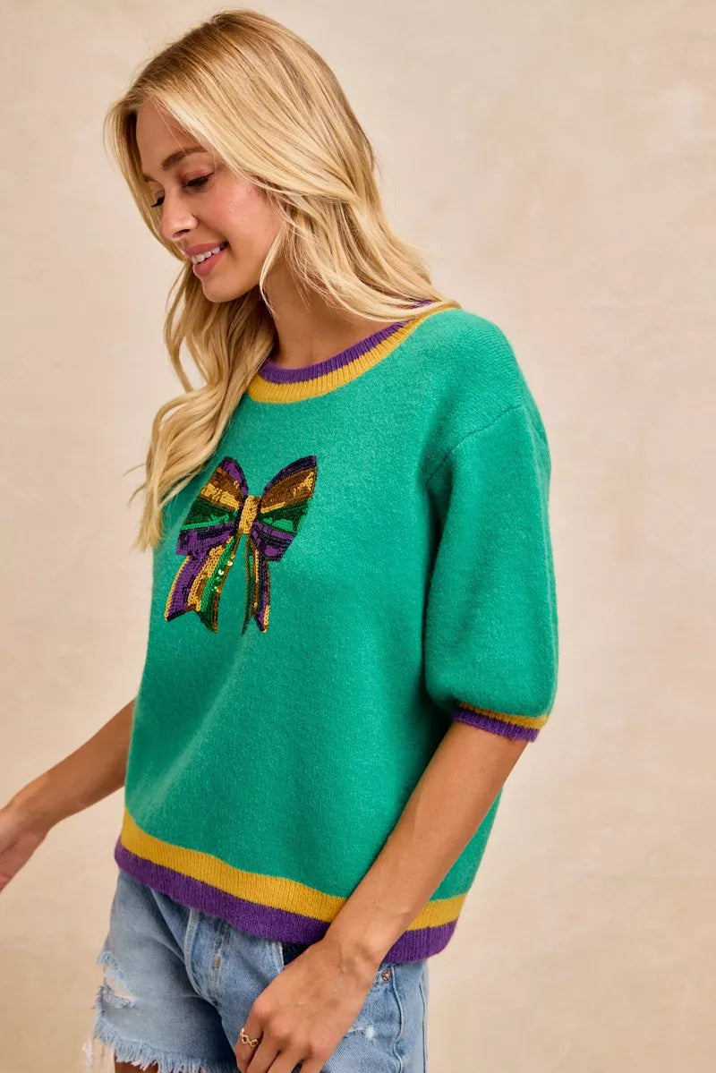 BiBi Mardi Gras Sequin Ribbon Patched Sweater featuring vibrant sequin bow design and playful colors.