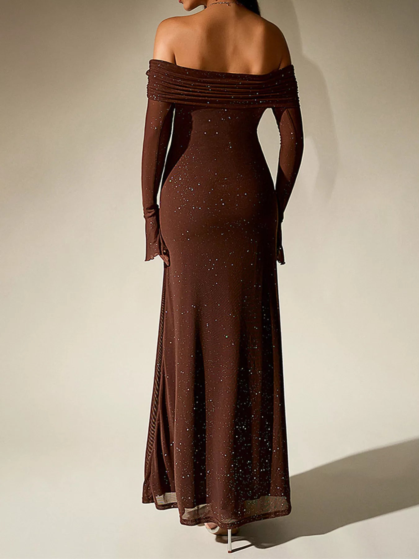 Model wearing a Glitter Off-Shoulder Maxi Dress from the back, showcasing its fitted design and sparkling embellishments.