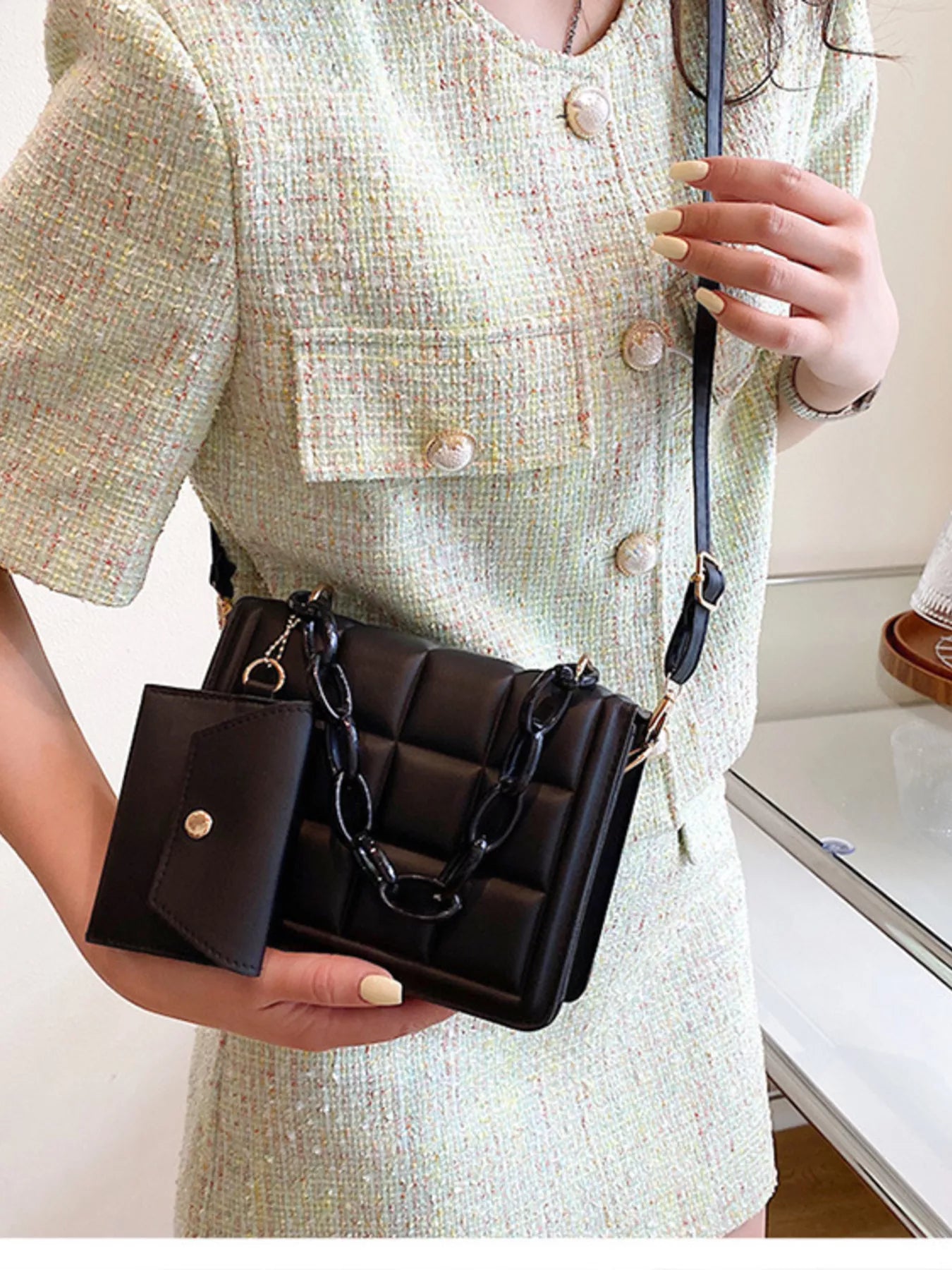 Woman holding a Quilted Chain Strap Crossbody Bag, showcasing its mini size and sleek PU leather design.