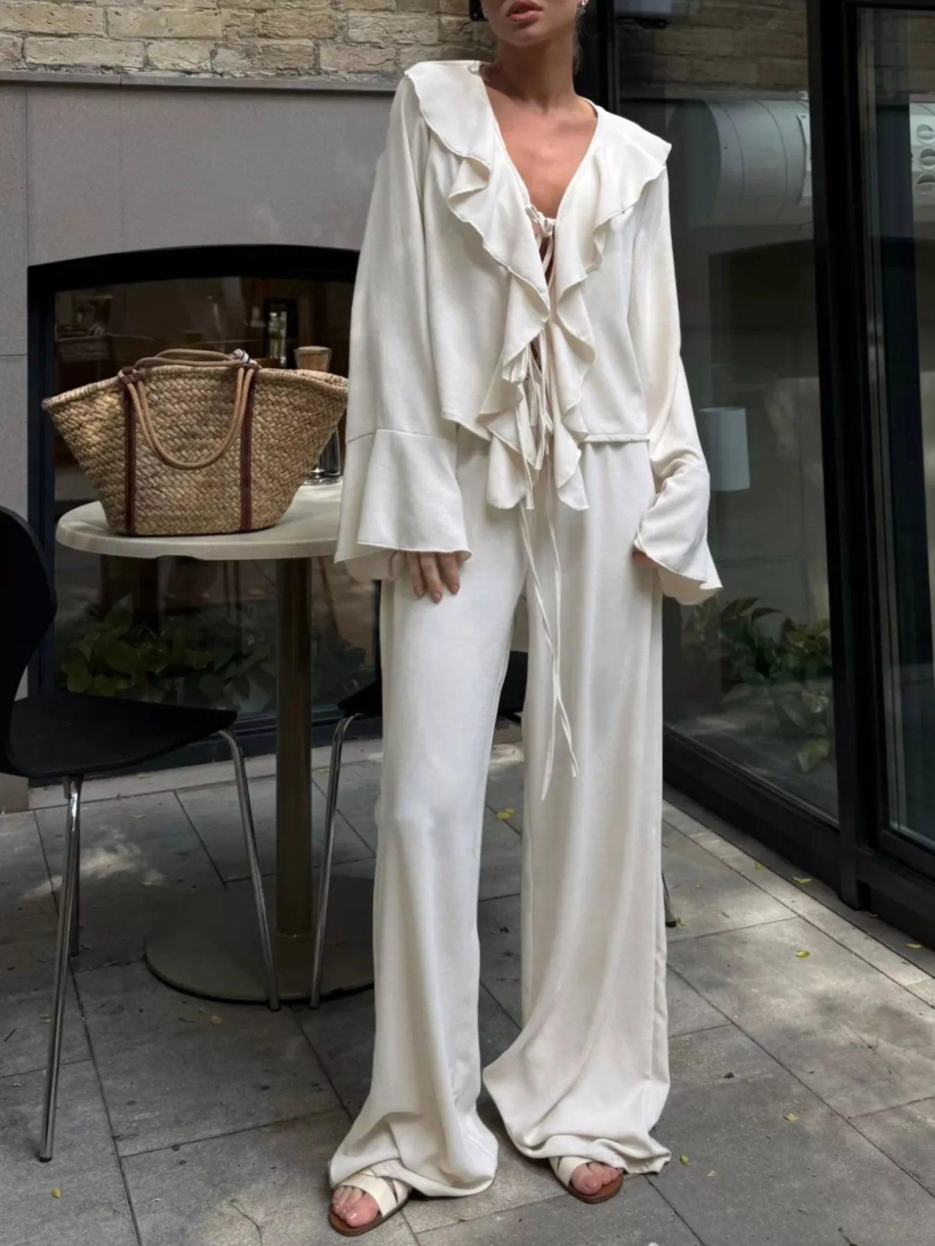 Ruffle Trim Tie Front Top and Pants Set for Women worn by model in a stylish outdoor setting, featuring ruffled design and tied front.