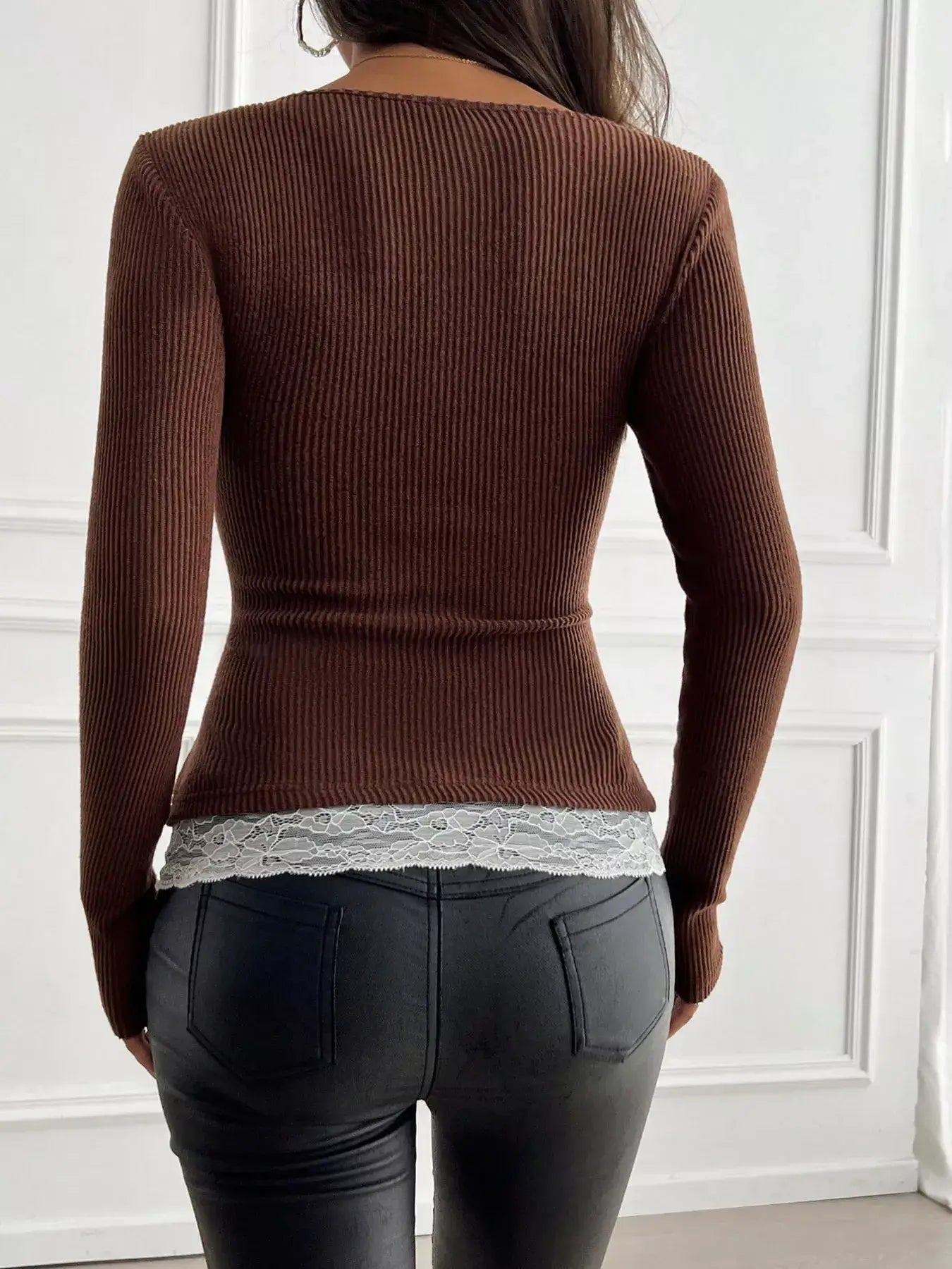 Back view of a brown ribbed long sleeve top featuring lace detail at the hem, styled with black jeans.