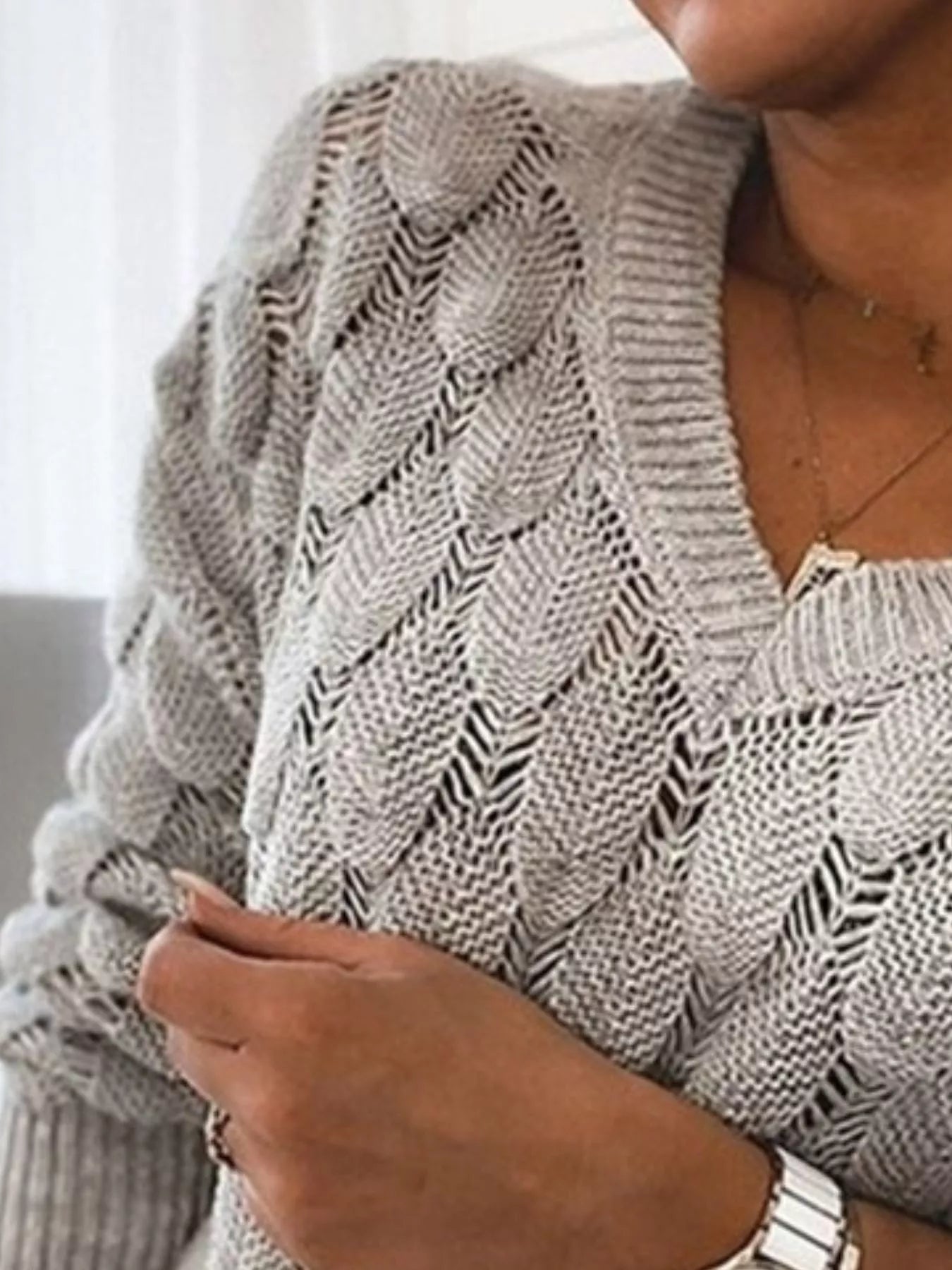 Close-up of a woman wearing a V-Neck Knitted Sweater in grey, showcasing its openwork knit design.