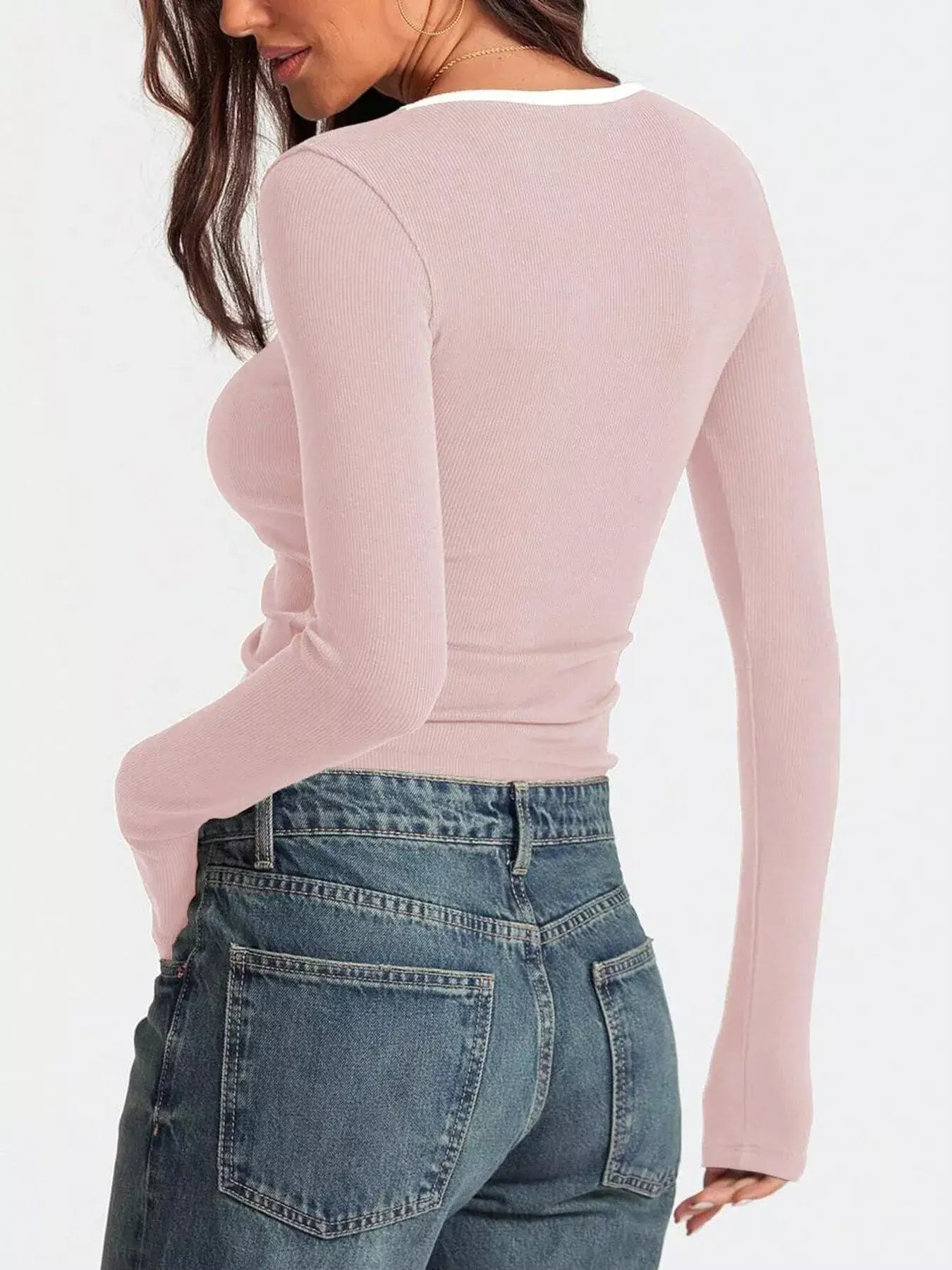 Back view of a woman wearing a pink scoop neck long sleeve t-shirt paired with high-waisted jeans.