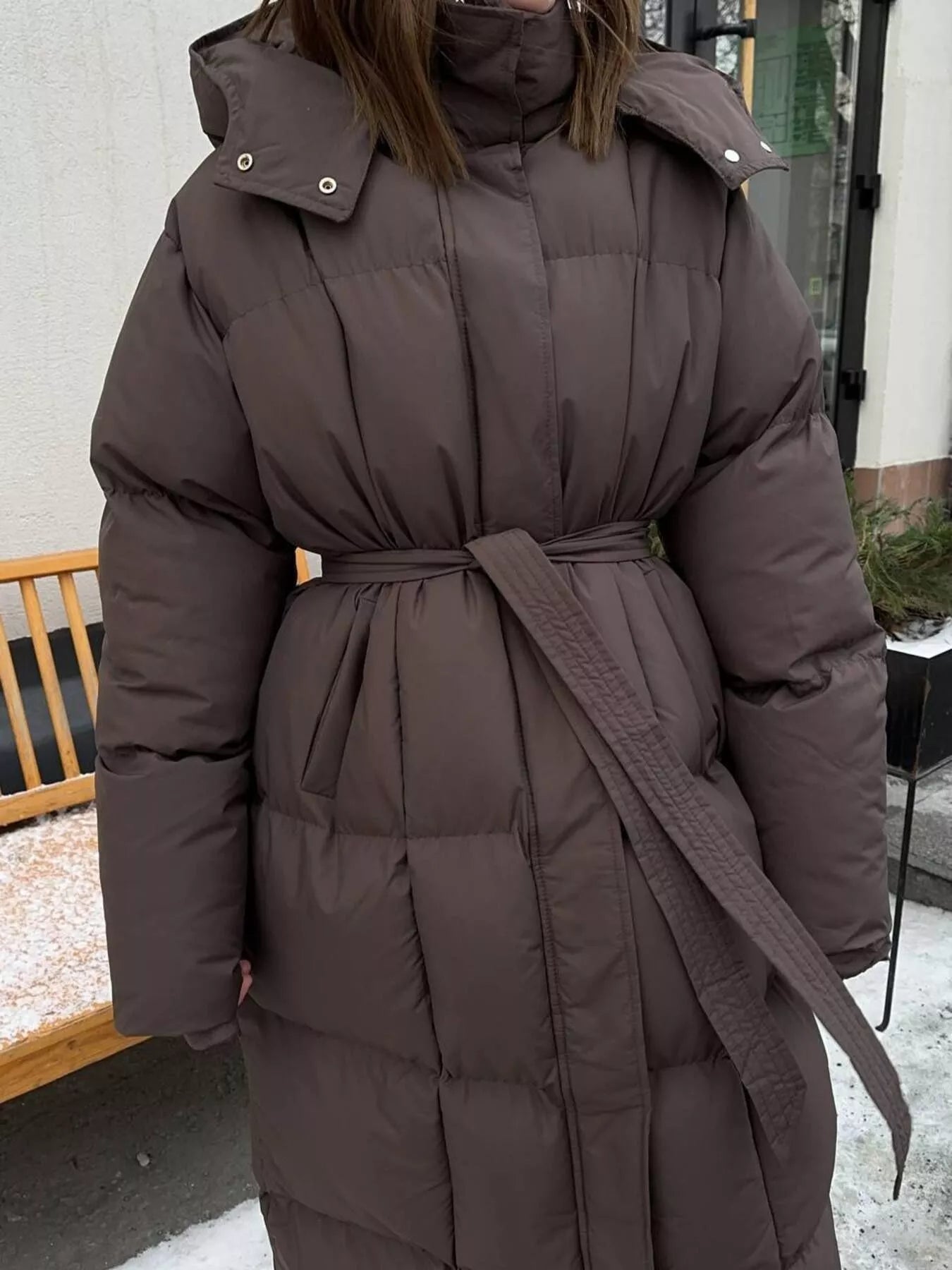 Longline Padded Winter Coat Belted worn by a woman, featuring a warm design with a belted waist.