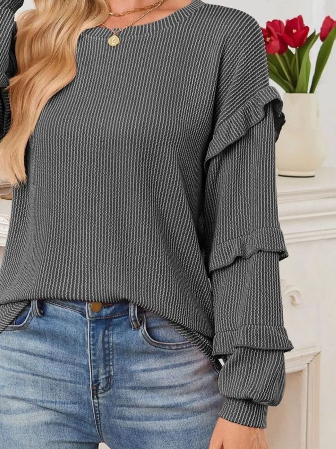 Ruffled Round Neck Long Sleeve Sweatshirt in gray with ruffled sleeves, styled with casual jeans and decorated background.