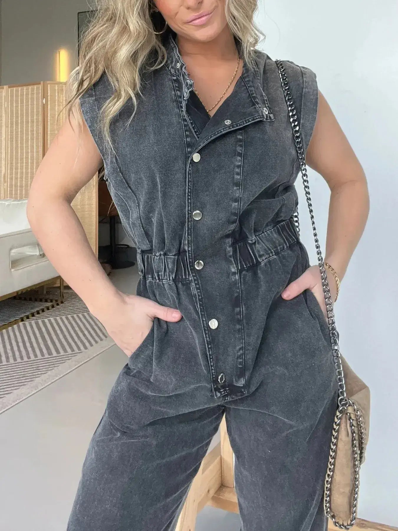 Plus size model wearing a stylish gray denim jumpsuit with cap sleeves and belted waist, perfect for casual outings.