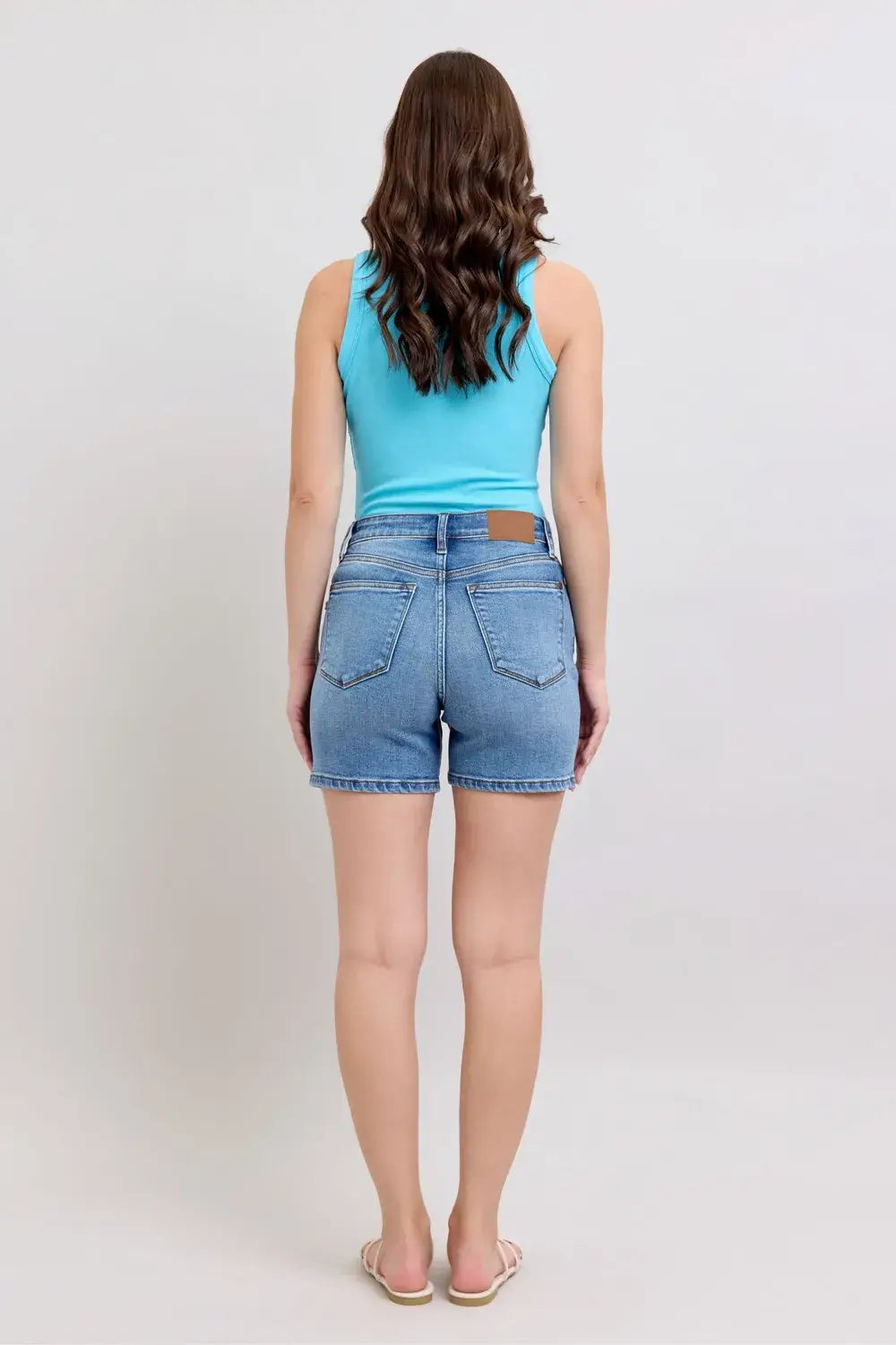 Model wearing Judy Blue denim shorts plus size, showcasing the back view with pockets and a classic design.