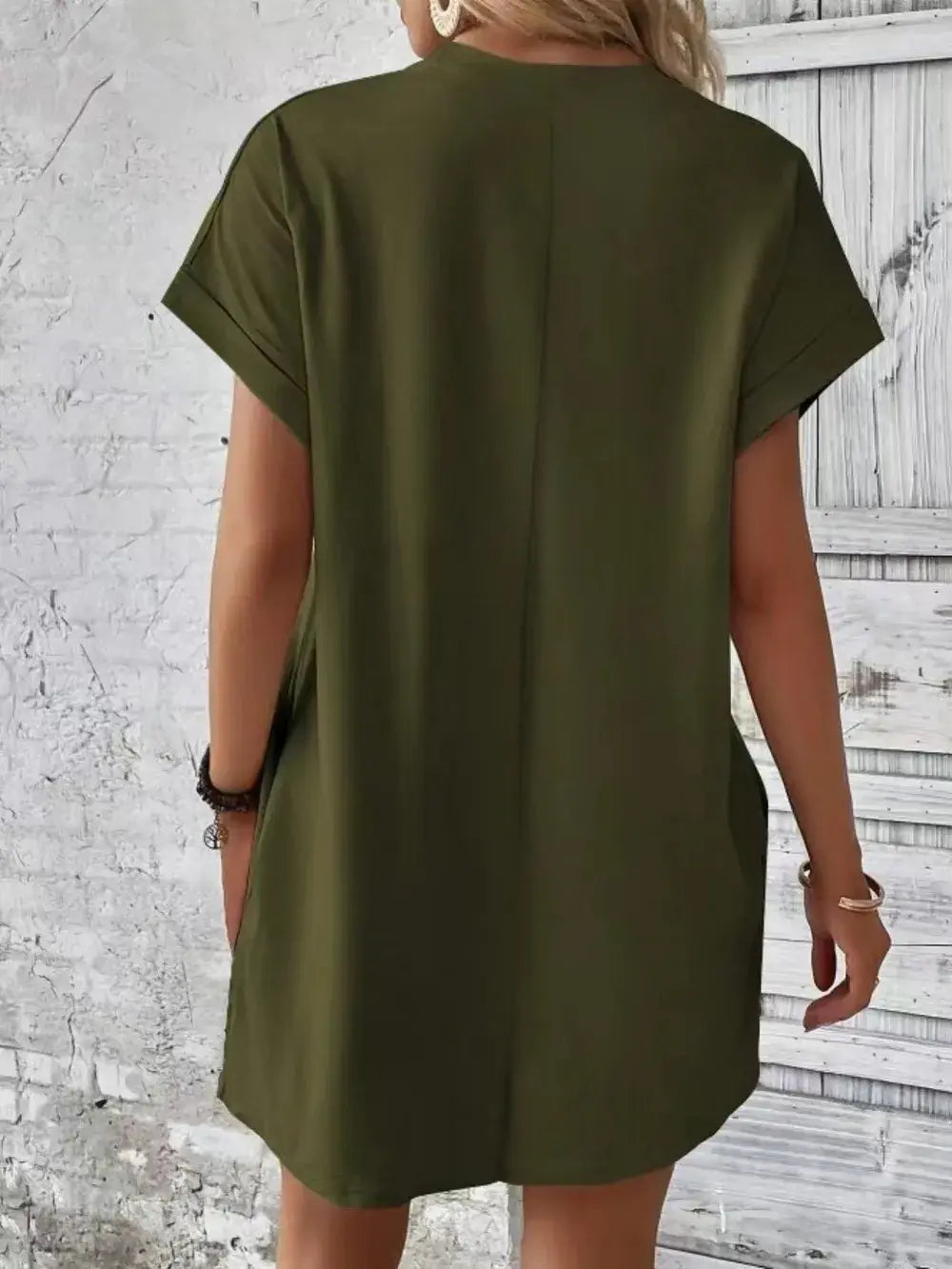 Back view of a casual pocketed green dress with short sleeves and a round neck design.