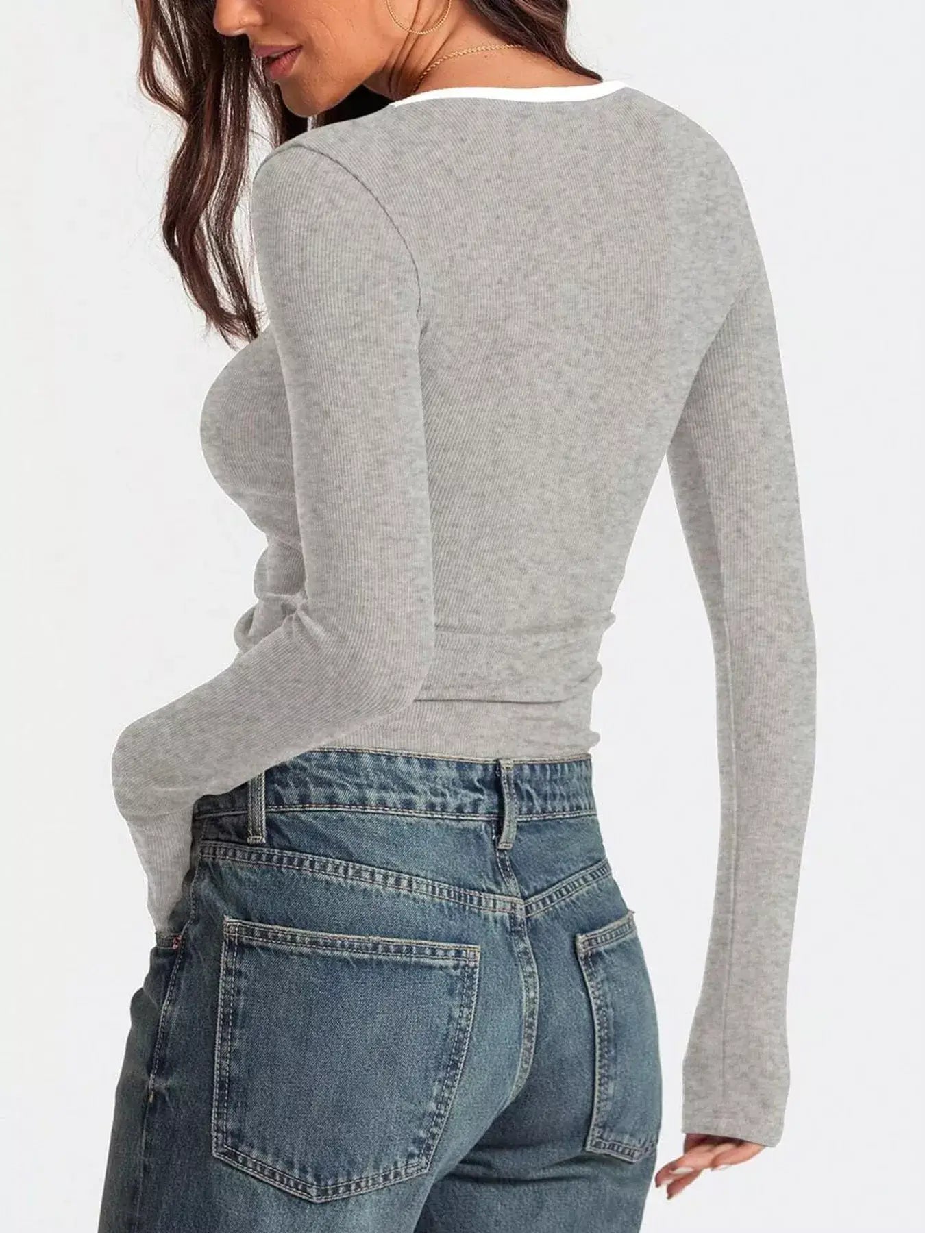 Back view of a woman wearing a gray scoop neck long sleeve t-shirt paired with high-waisted jeans.