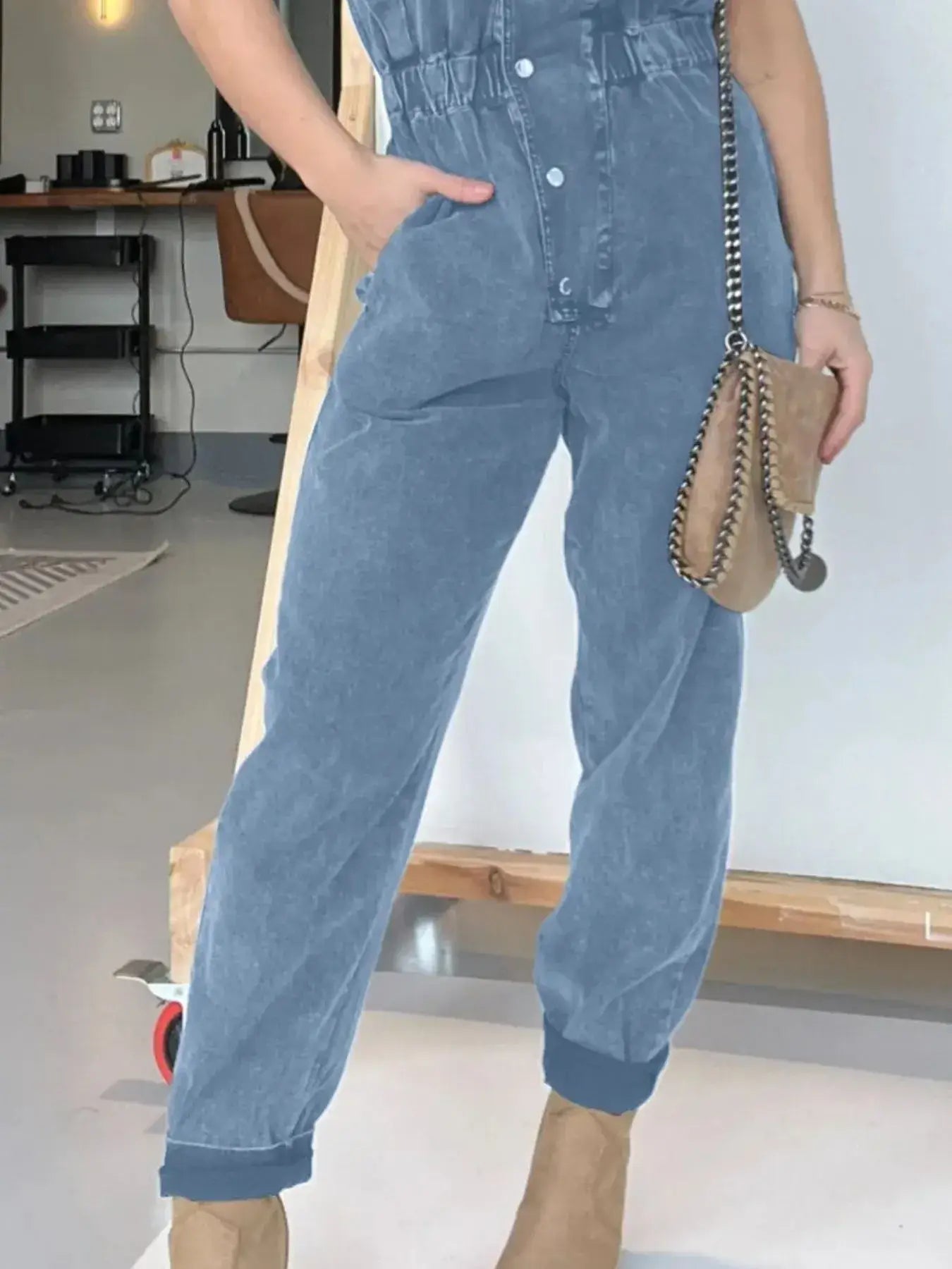 Model wearing a plus size button front cap sleeve denim jumpsuit with practical pockets and a belt.