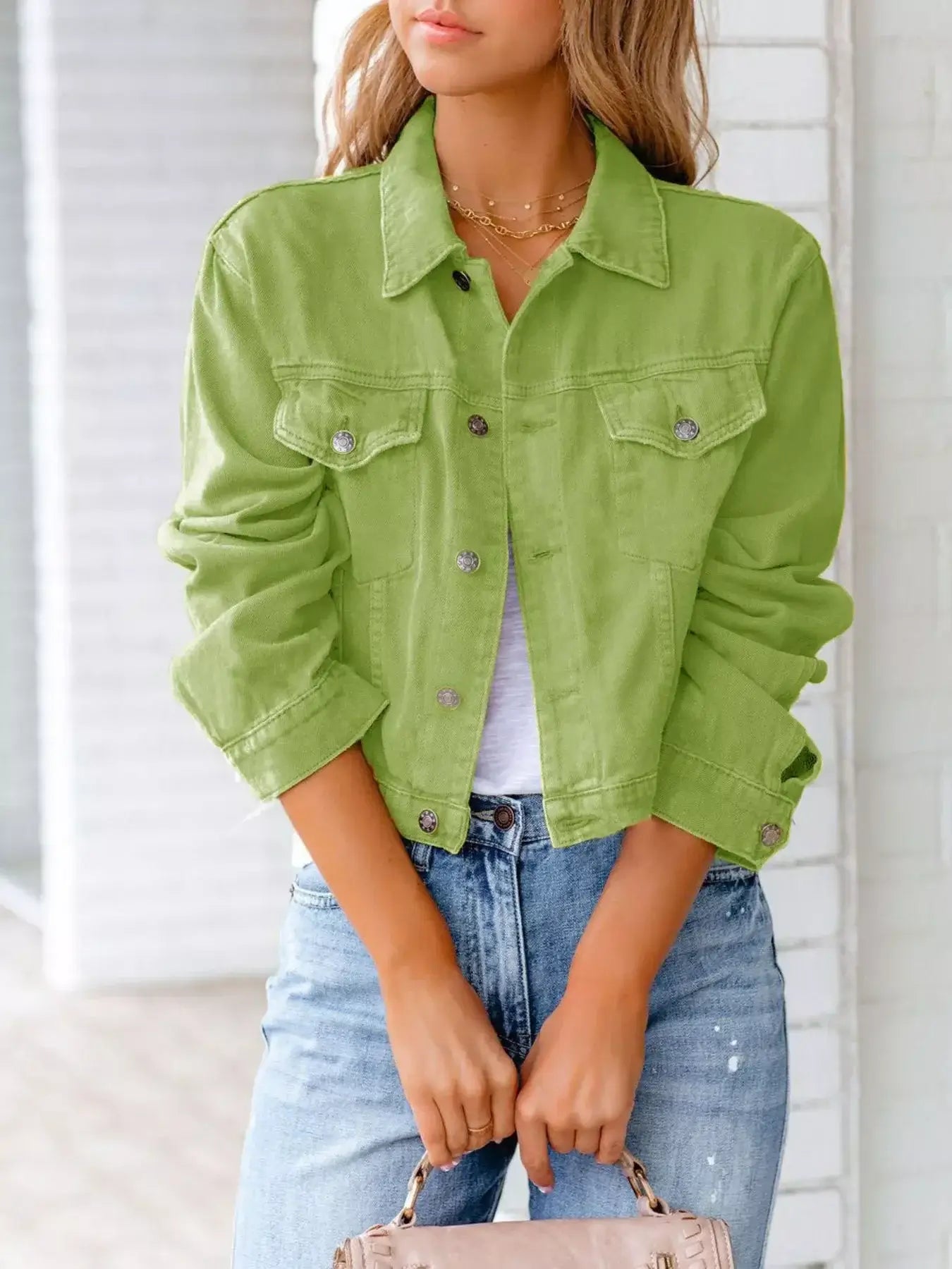 Stylish woman wearing a green button-up denim jacket with long sleeves over casual outfit.