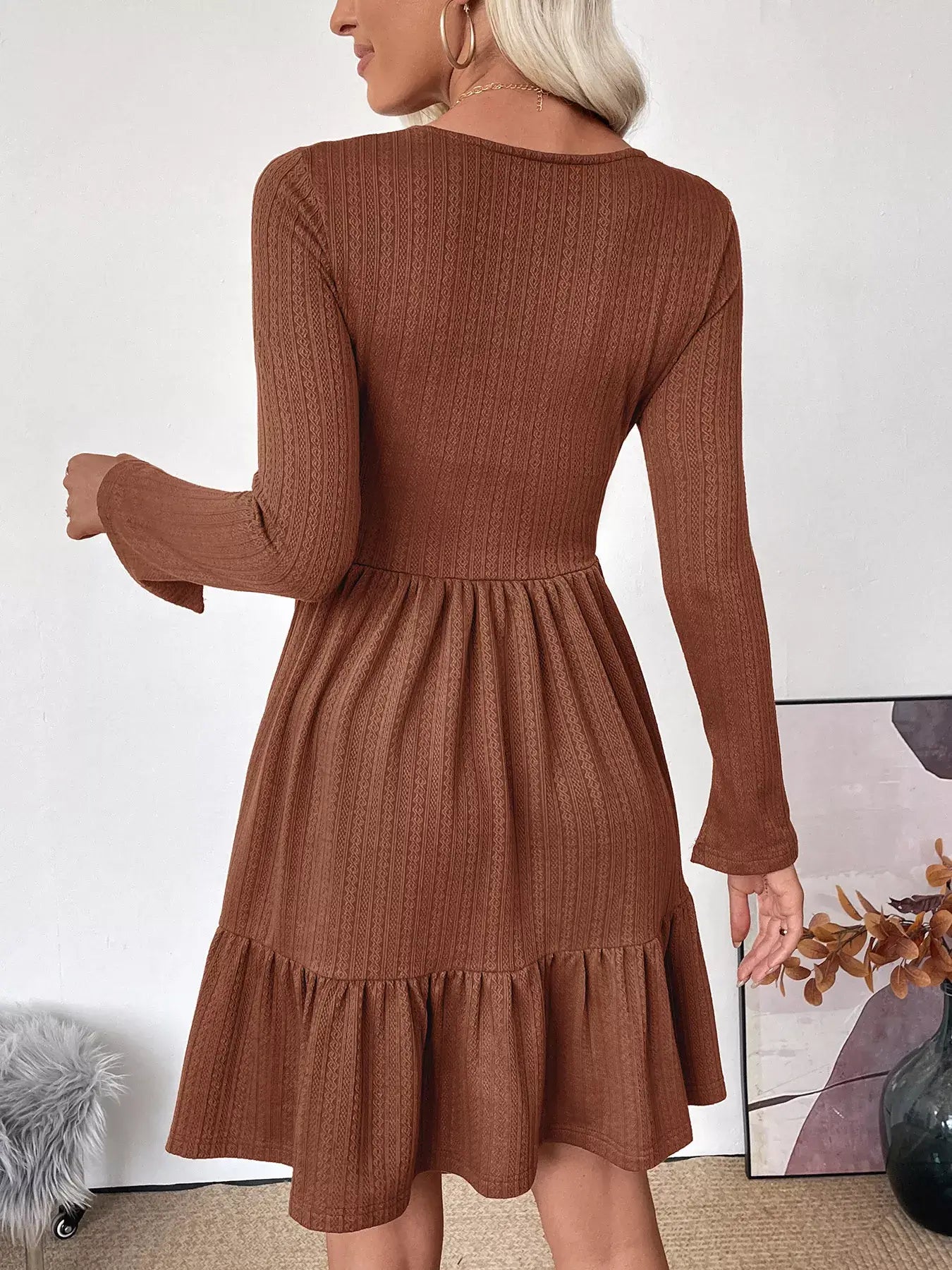 Back view of a woman wearing a Ruffled Hem Long Sleeve Knit Dress, showcasing the ruffled hemline and long sleeves.