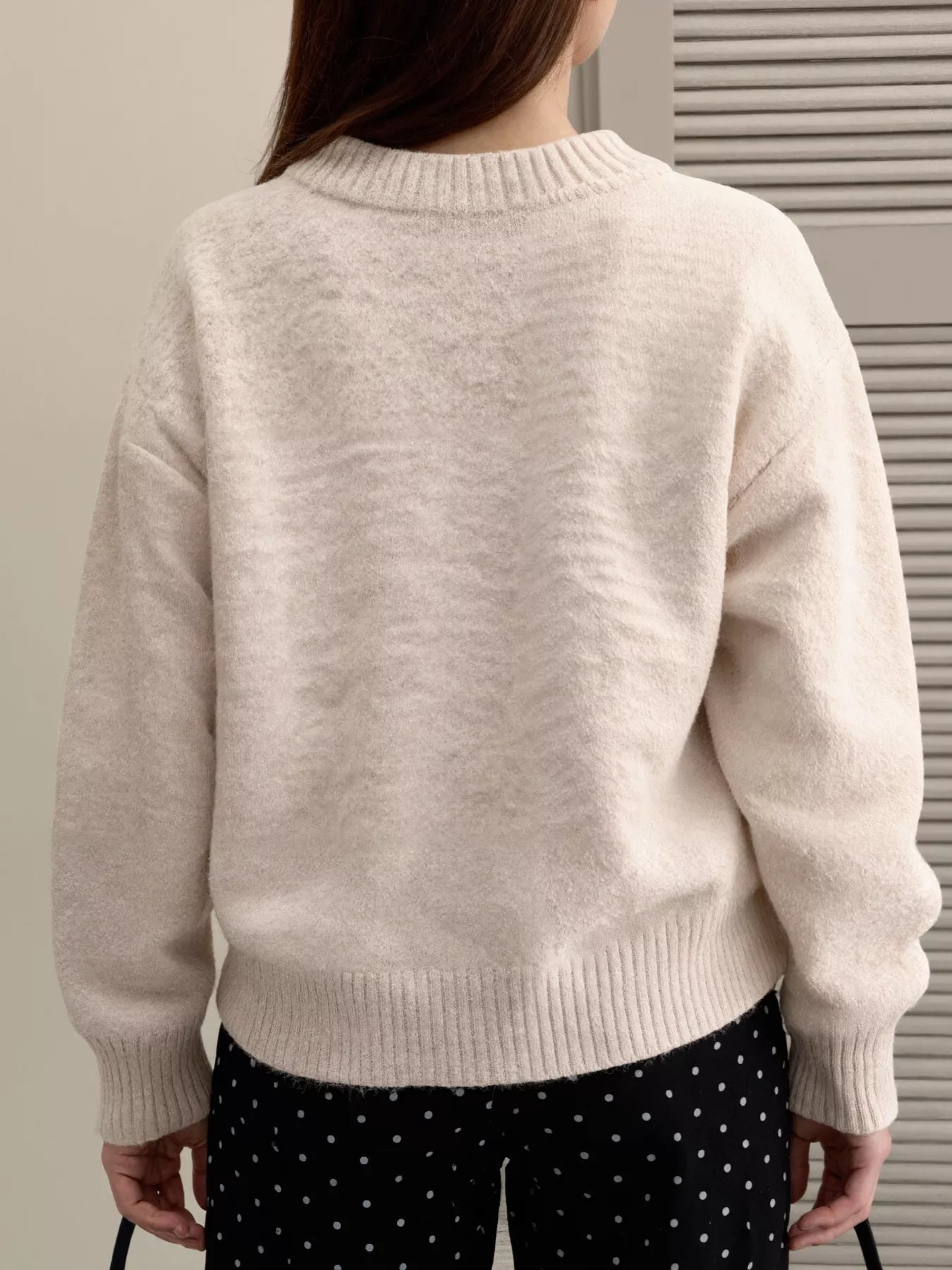 Back view of a woman wearing a Lace Bowknot Knit Cardigan, showcasing its soft, slightly stretchy fabric and cozy fit.
