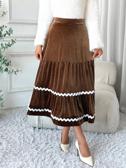 A woman wearing a Velvet Tiered Midi Skirt with a ruched design, styled for elegance and versatility.