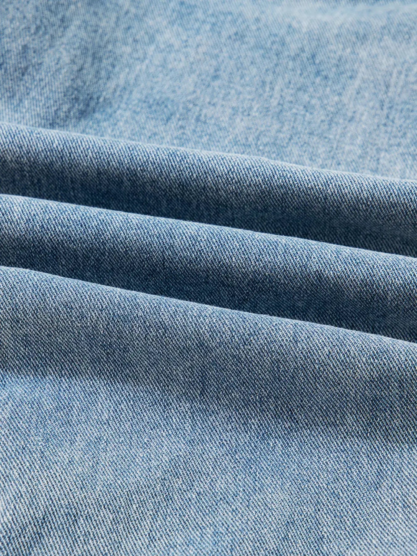 Close-up of soft, blue denim fabric with folded texture showing quality for stylish jackets.