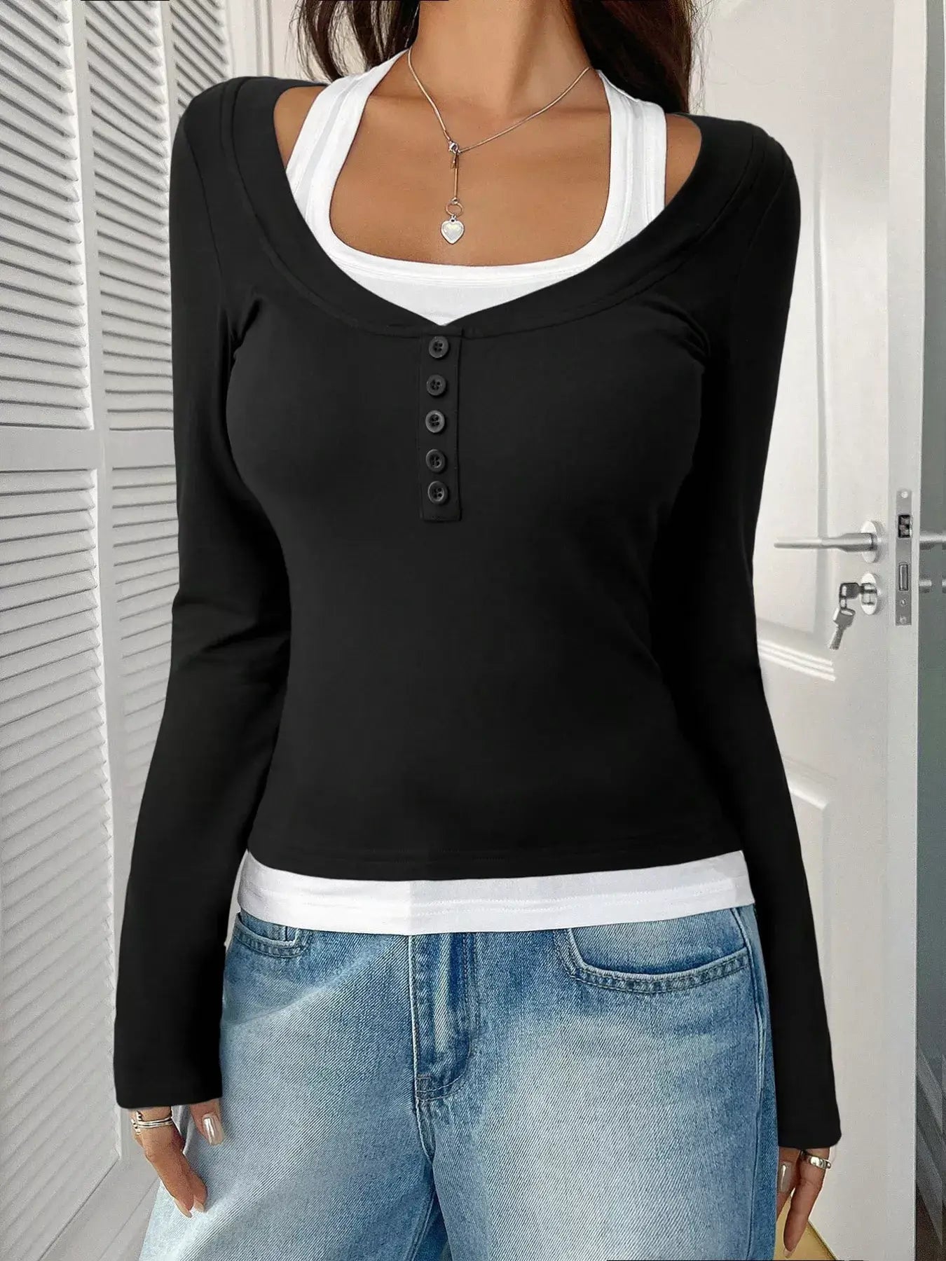 Chic scoop neck long sleeve t-shirt layered with a white tank top, paired with denim jeans.