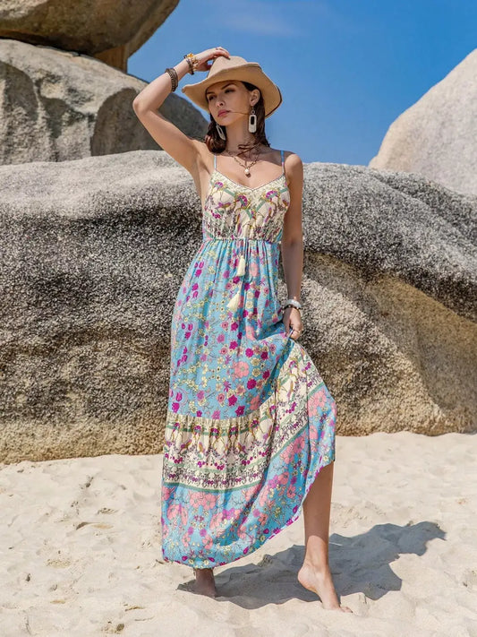 Model wearing a Tassel Floral Print Cami Dress on the beach with a straw hat and bohemian accessories.