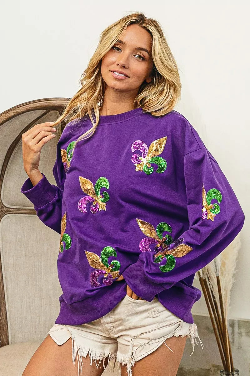 BiBi Fleur De Lis Sequin Patches Mardi Gras Sweatshirt in purple with colorful sequins worn by a model.